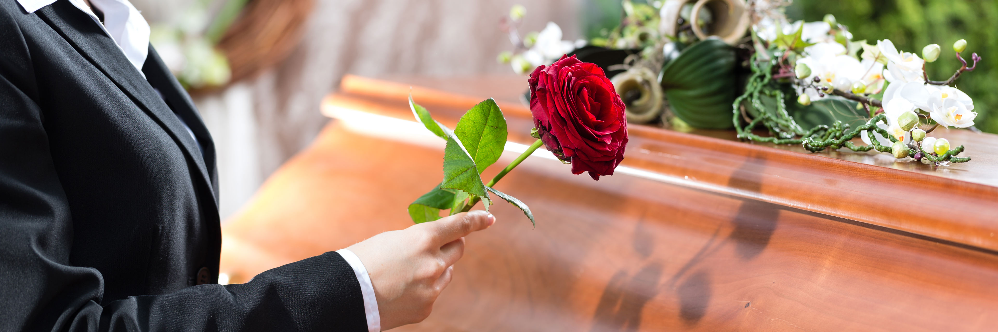 Person med rose ved kiste