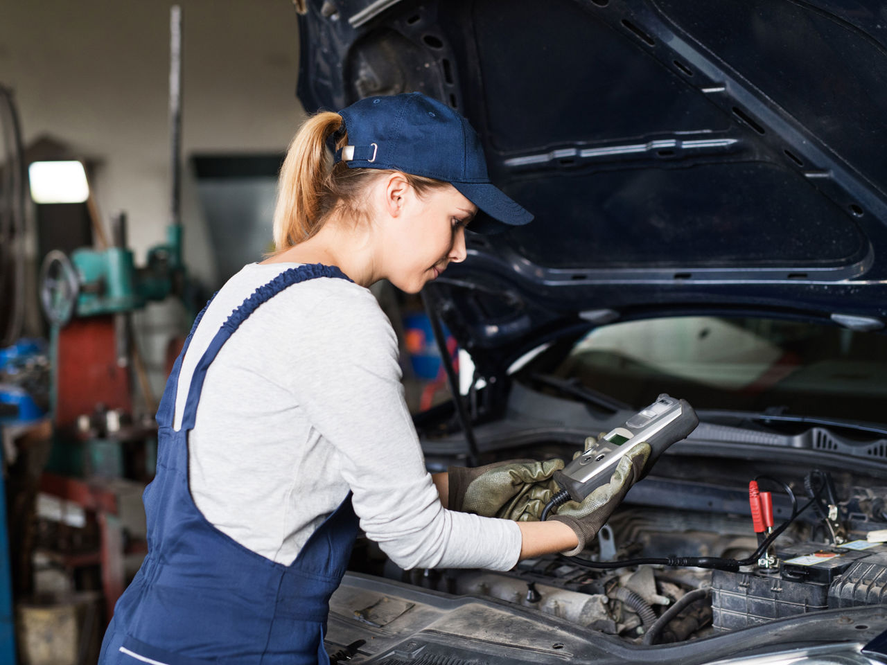 Pige i arbejdstøj der roder med biler