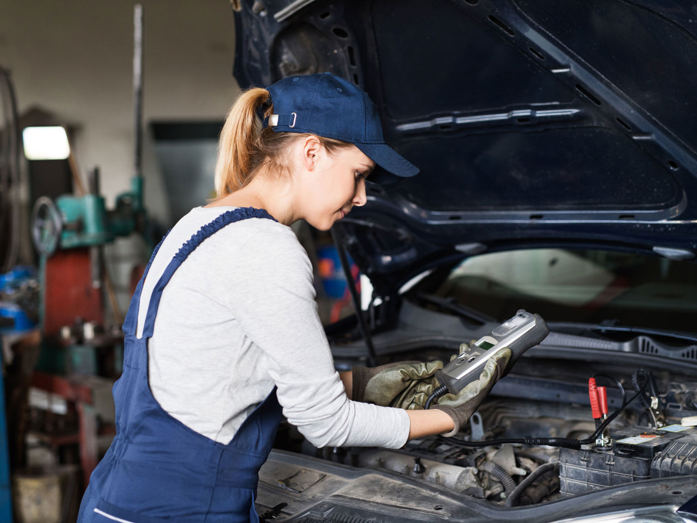Pige i arbejdstøj der roder med biler