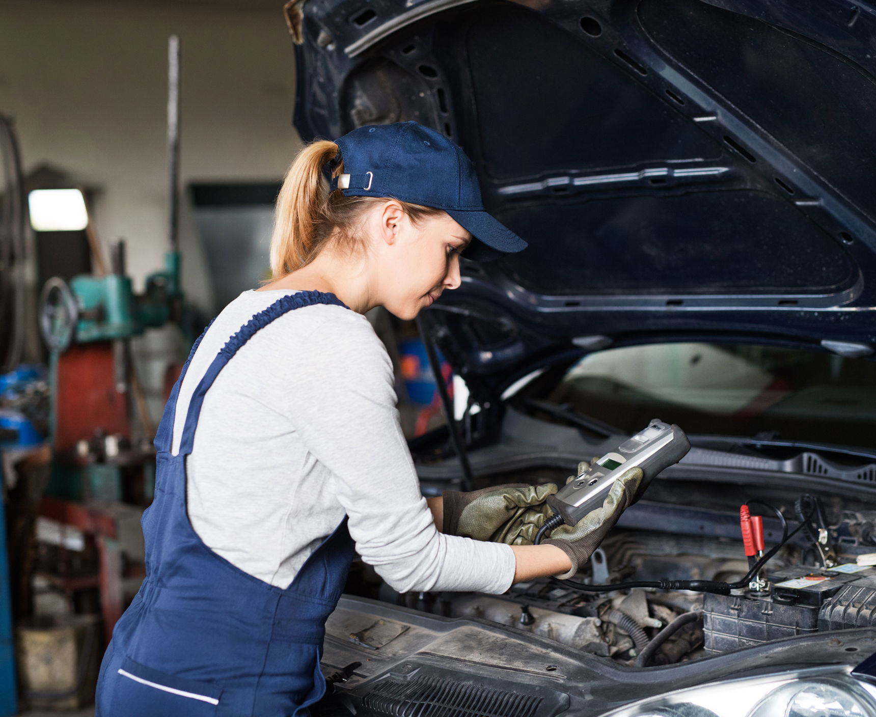 Pige i arbejdstøj der roder med biler