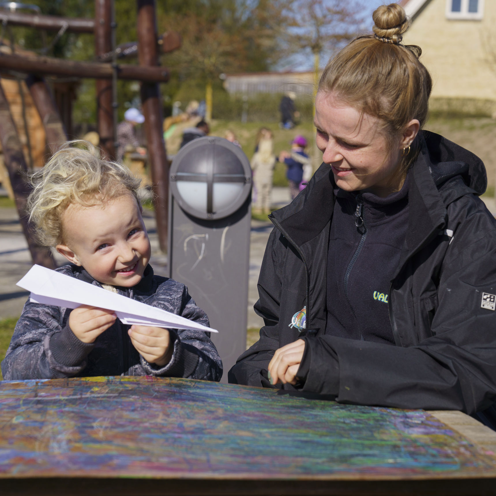 Barn med pædagog og en papirflyver i hånden