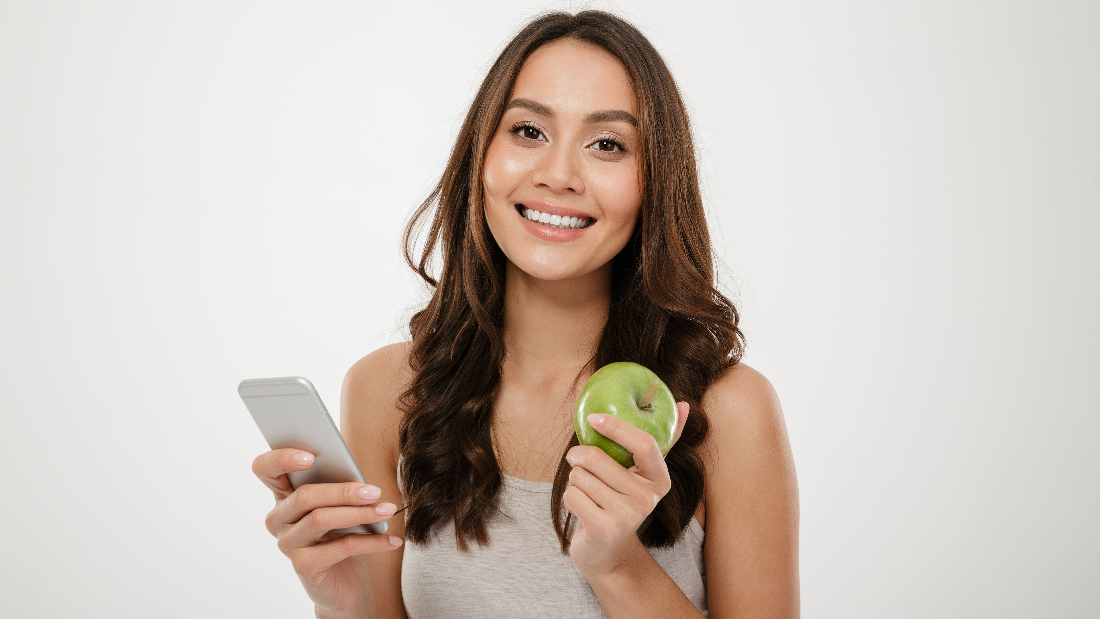 En ung kvinde der holder et æble og en mobil