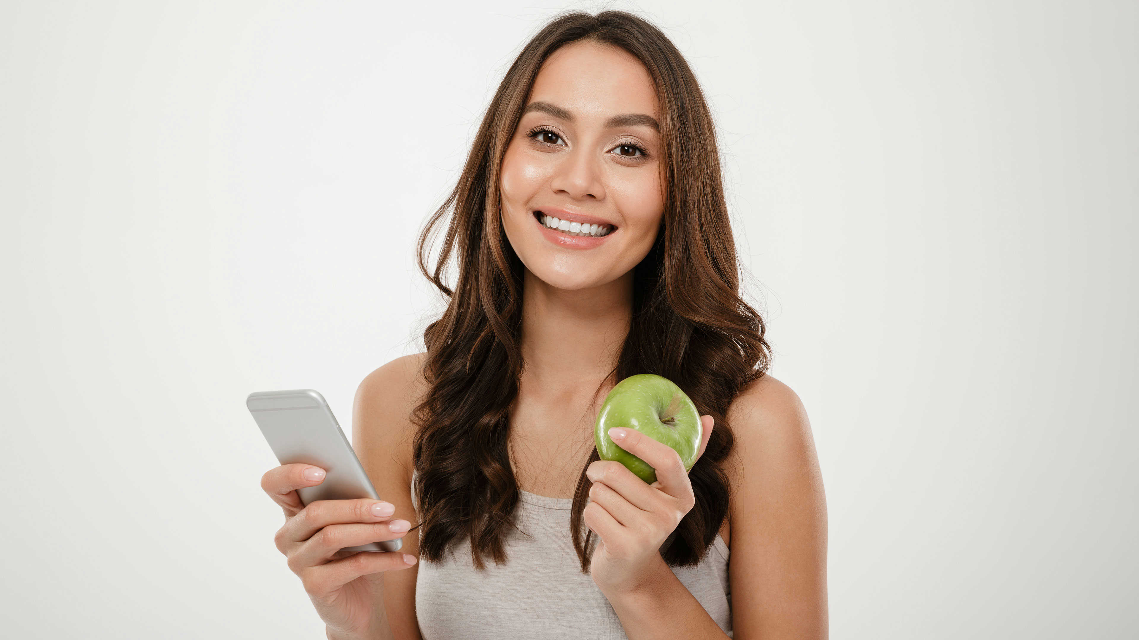 En ung kvinde der holder et æble og en mobil