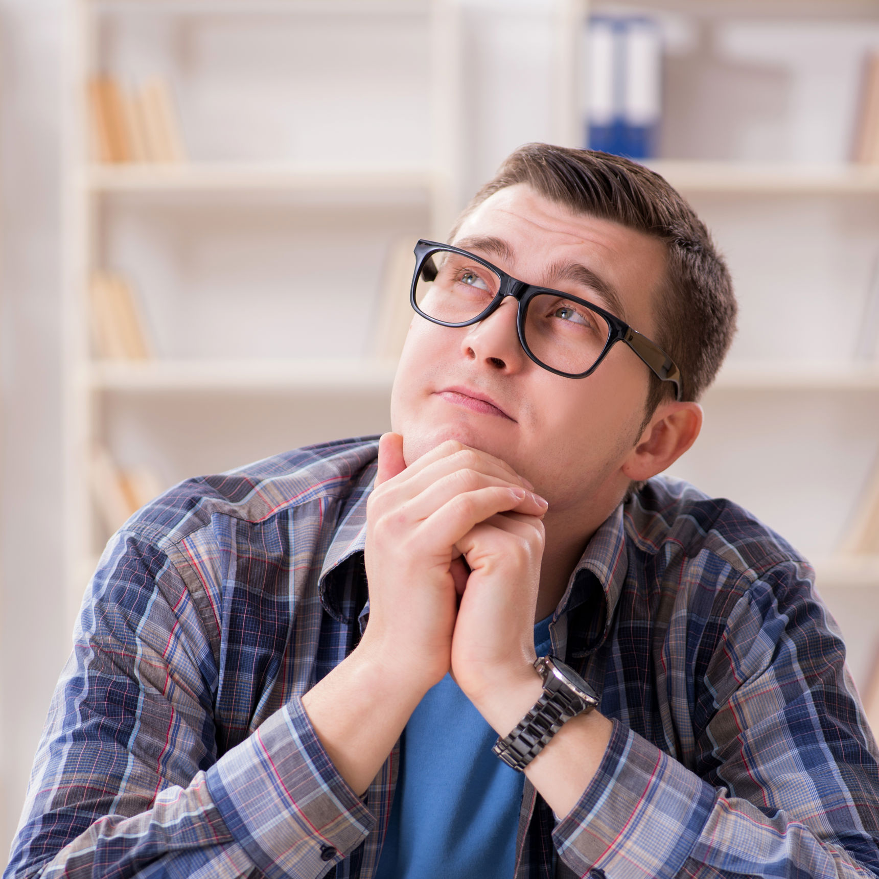 Tænkende ung mand foran nogle bøger