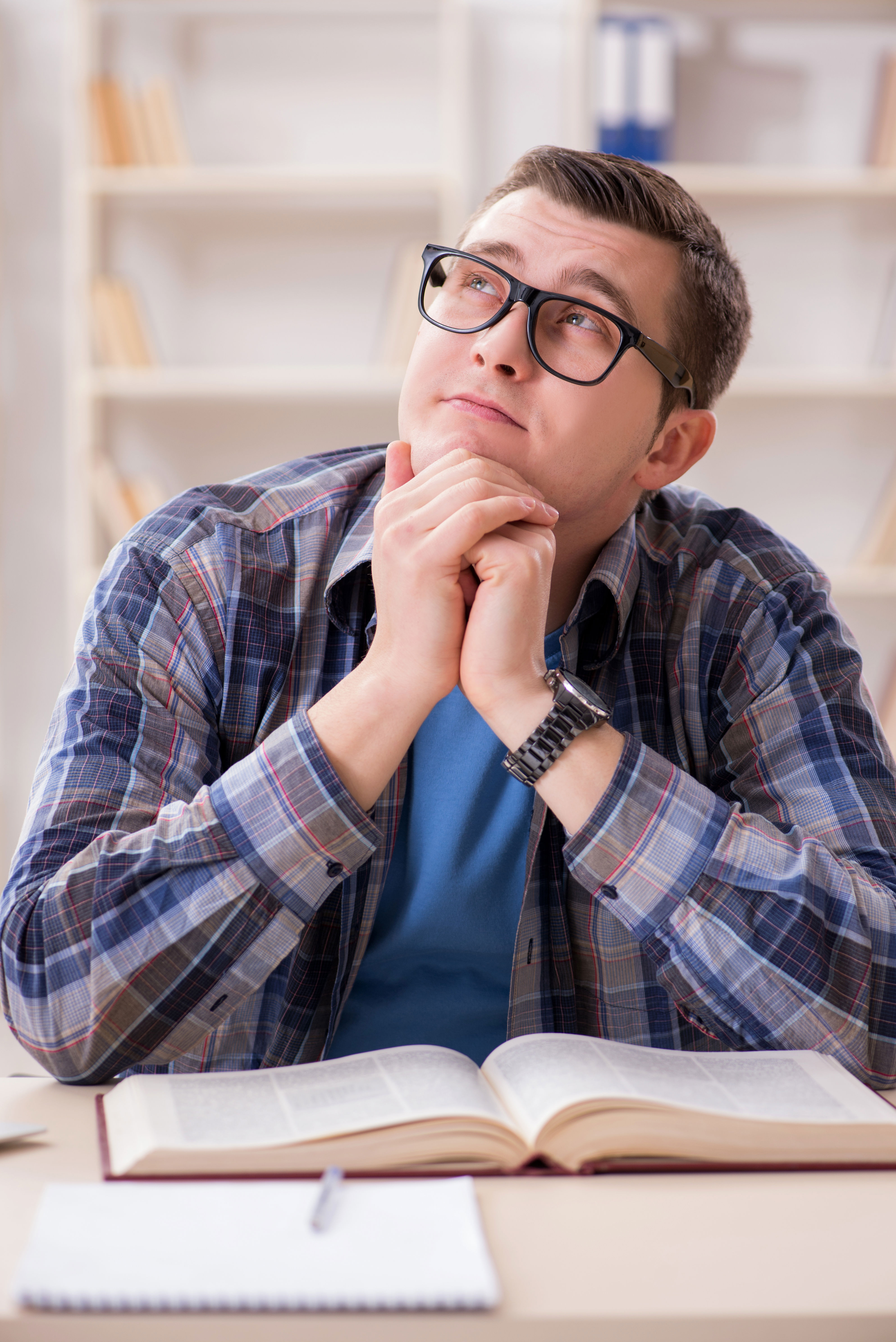 Tænkende ung mand foran nogle bøger