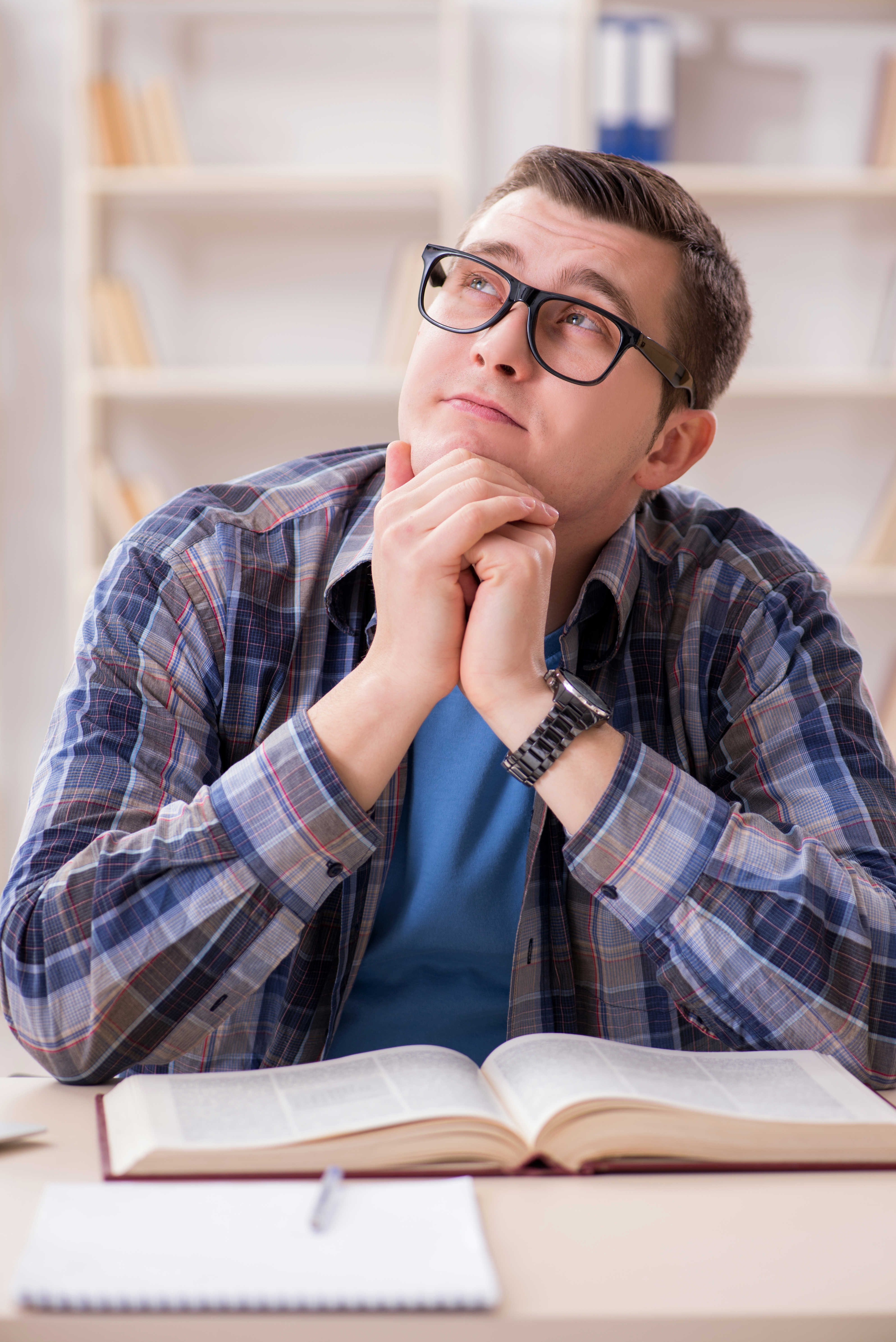 Tænkende ung mand foran nogle bøger