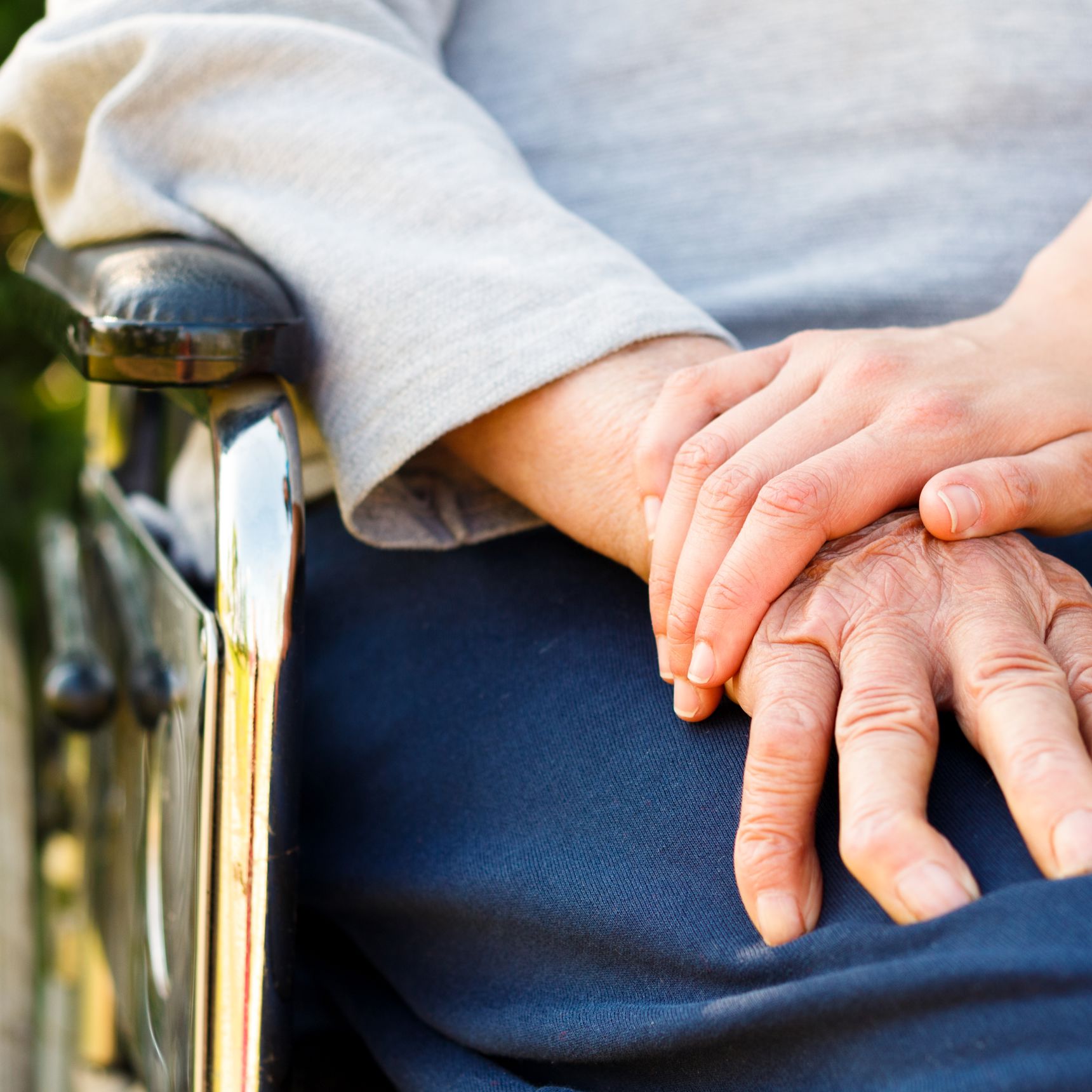 Kvinde der holder sin på en person i kørestol