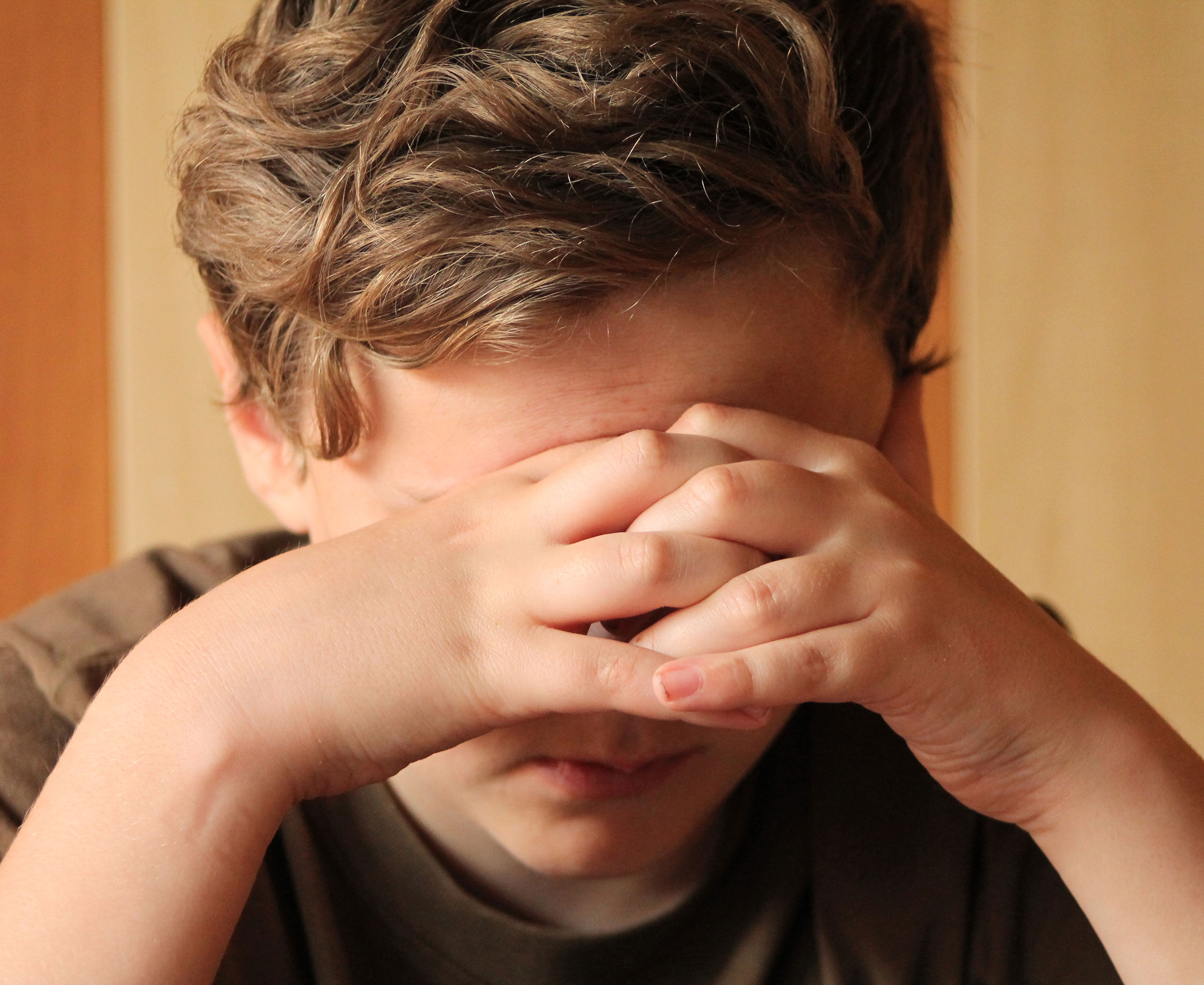 Trist dreng med hænderne for øjnene