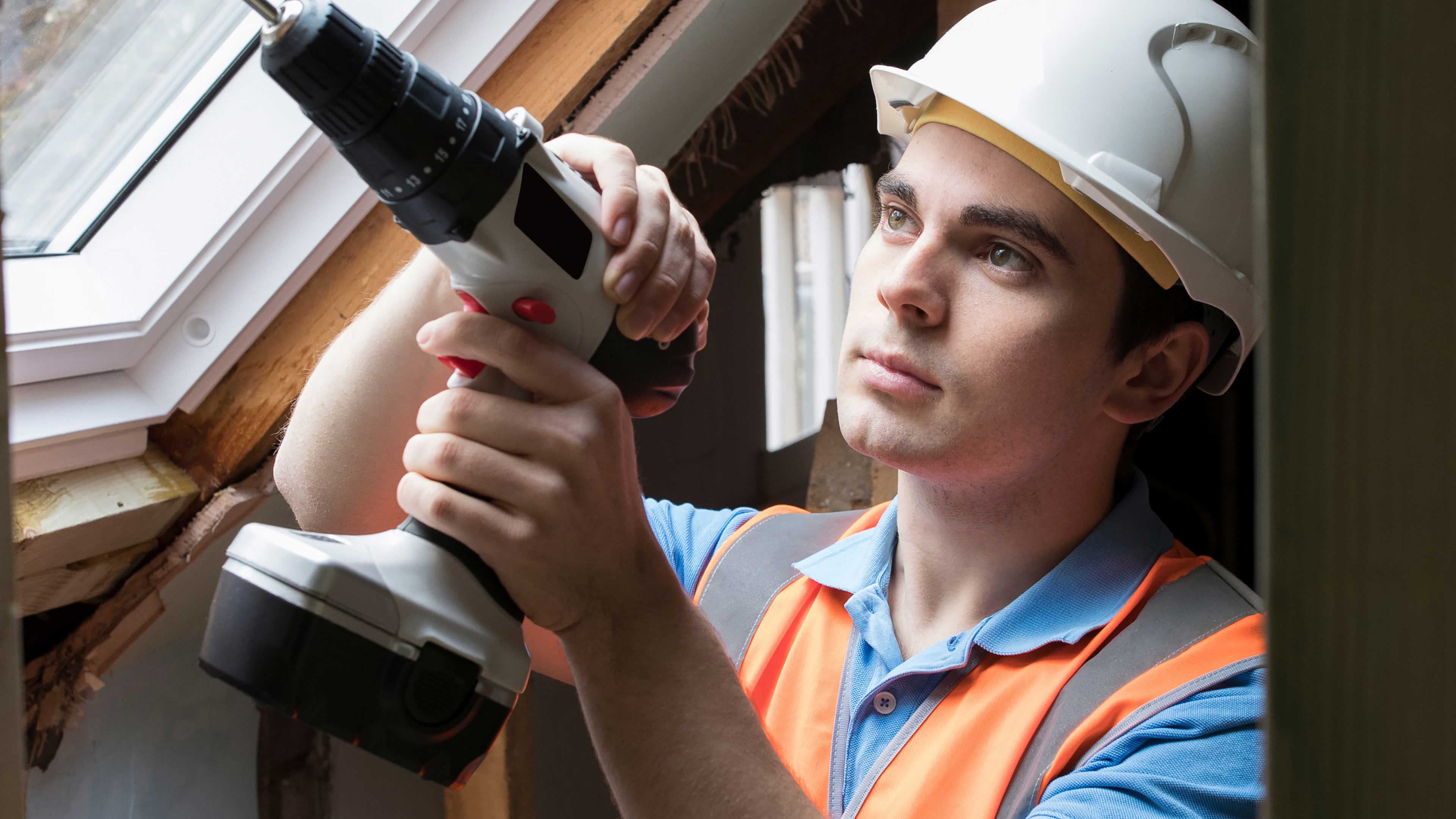 En mand med en skruemaskine og sikkerhedshjelm
