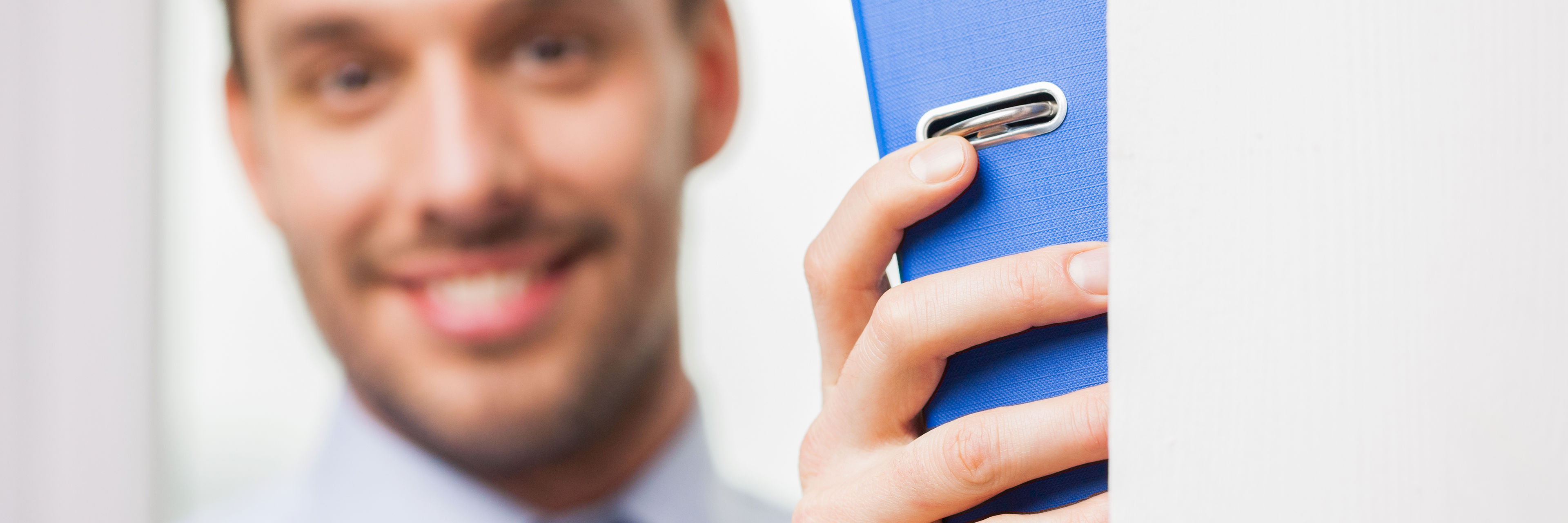 Mand smiler med ringbind i hånden