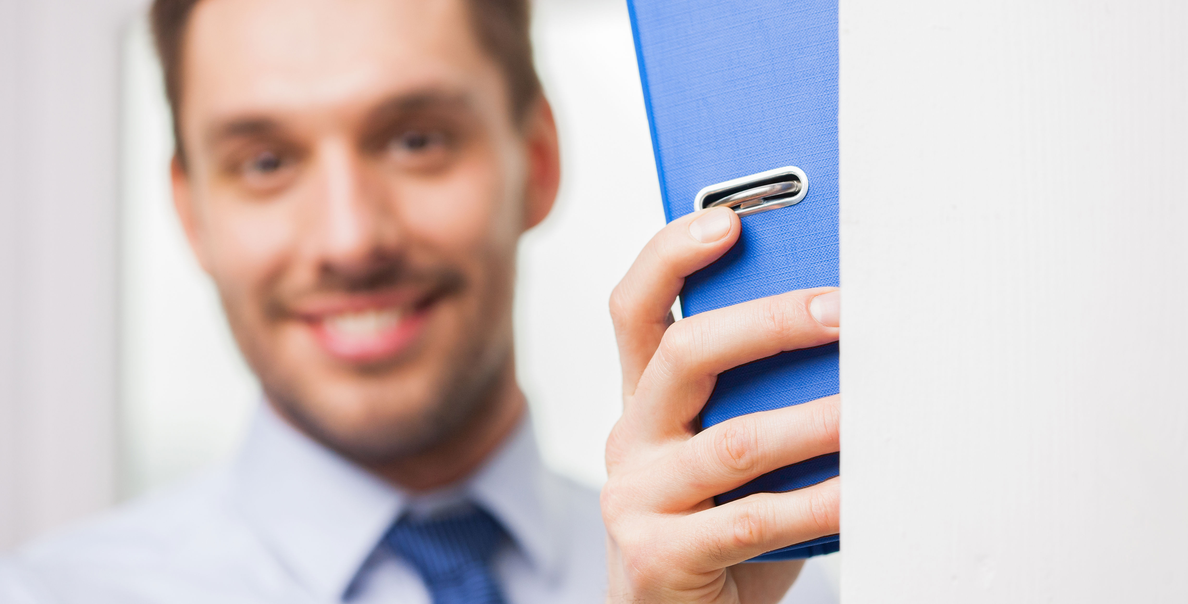 Mand smiler med ringbind i hånden