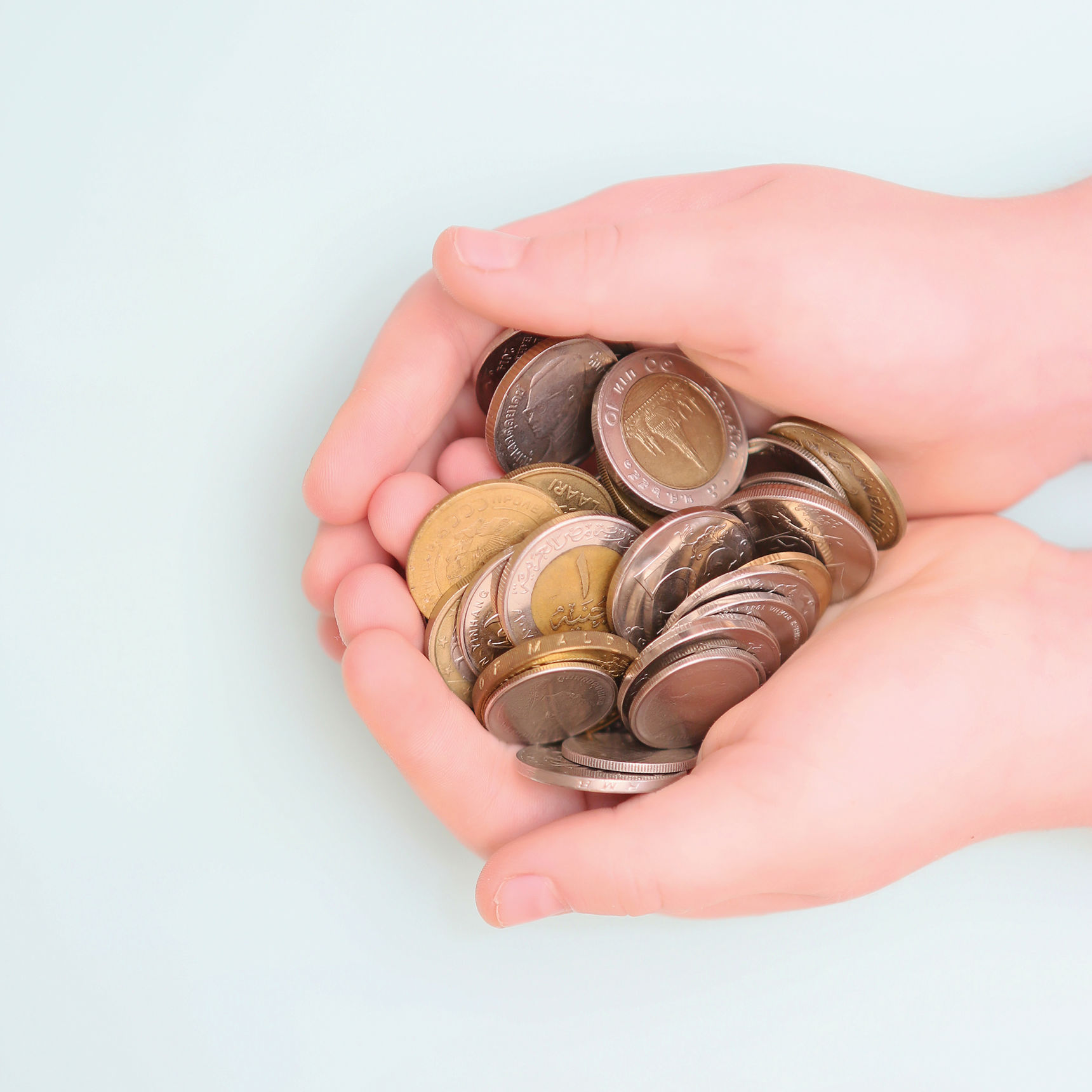 Hænder der holder en masse mønter
