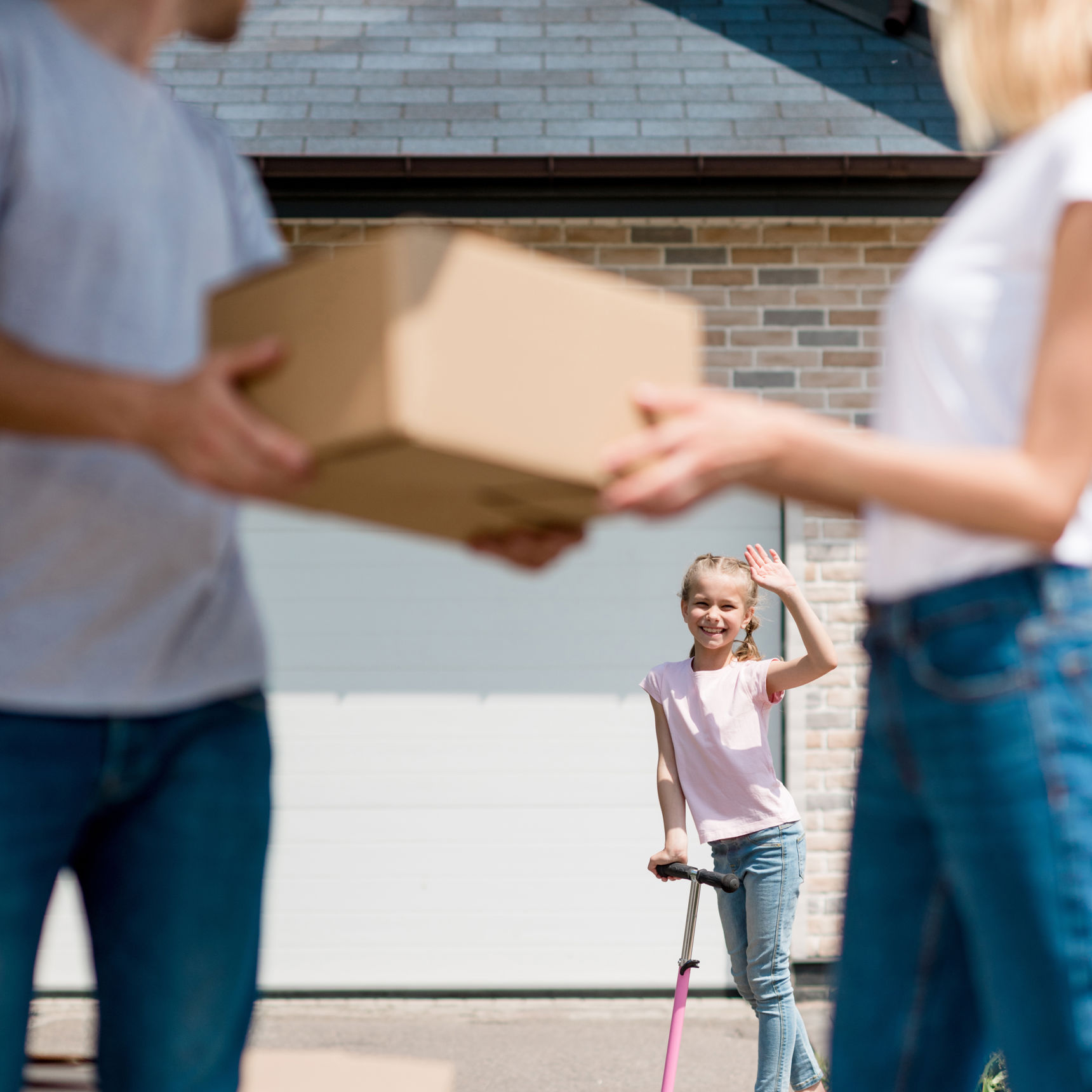 Forældre med en flyttekasse der kigger på deres datter i baggrunden