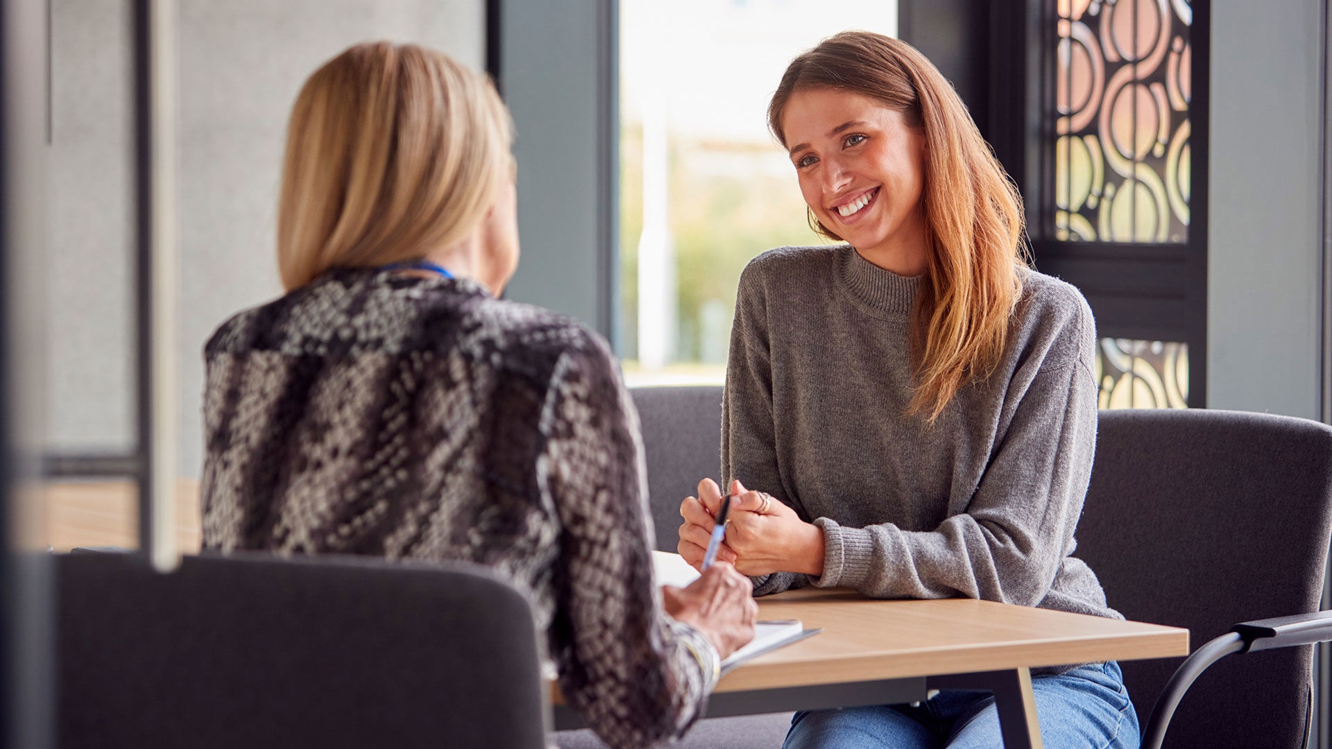 En kvinde modtager rådgivning af en anden kvinde med ryggen til