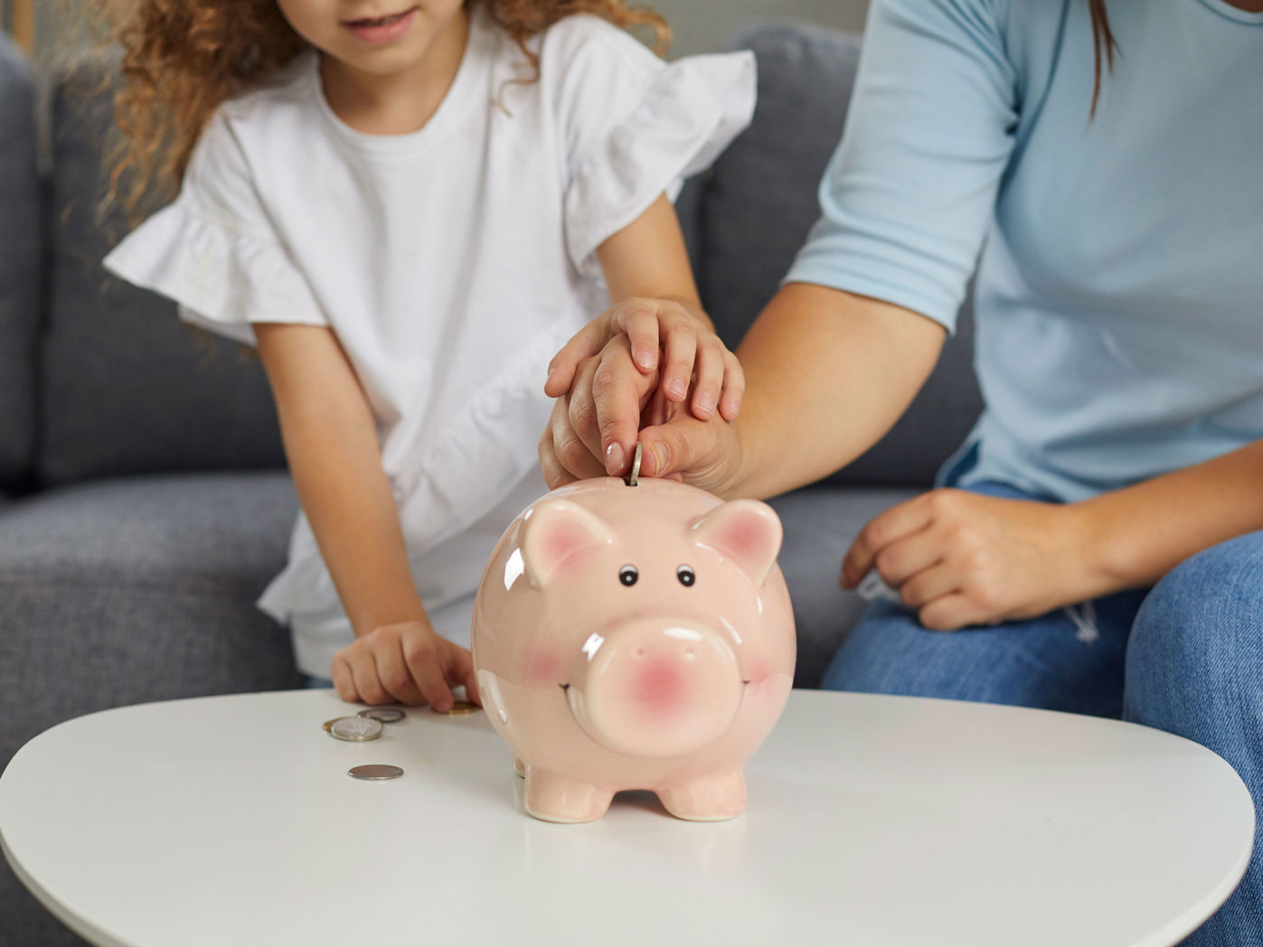 Mor og datter der putter penge i en sparegris