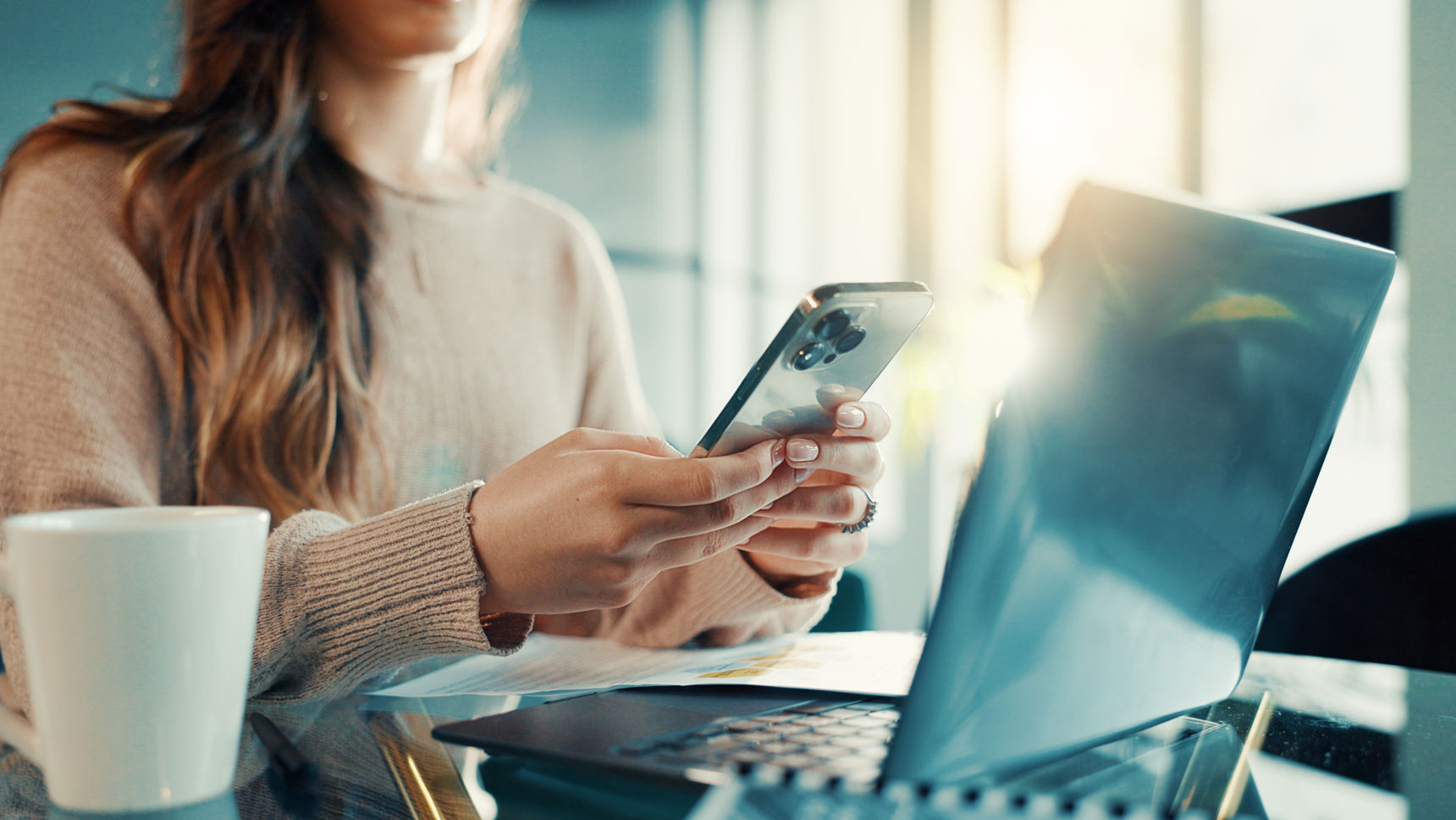 Kvinde der sidder med pc og mobiltelefon