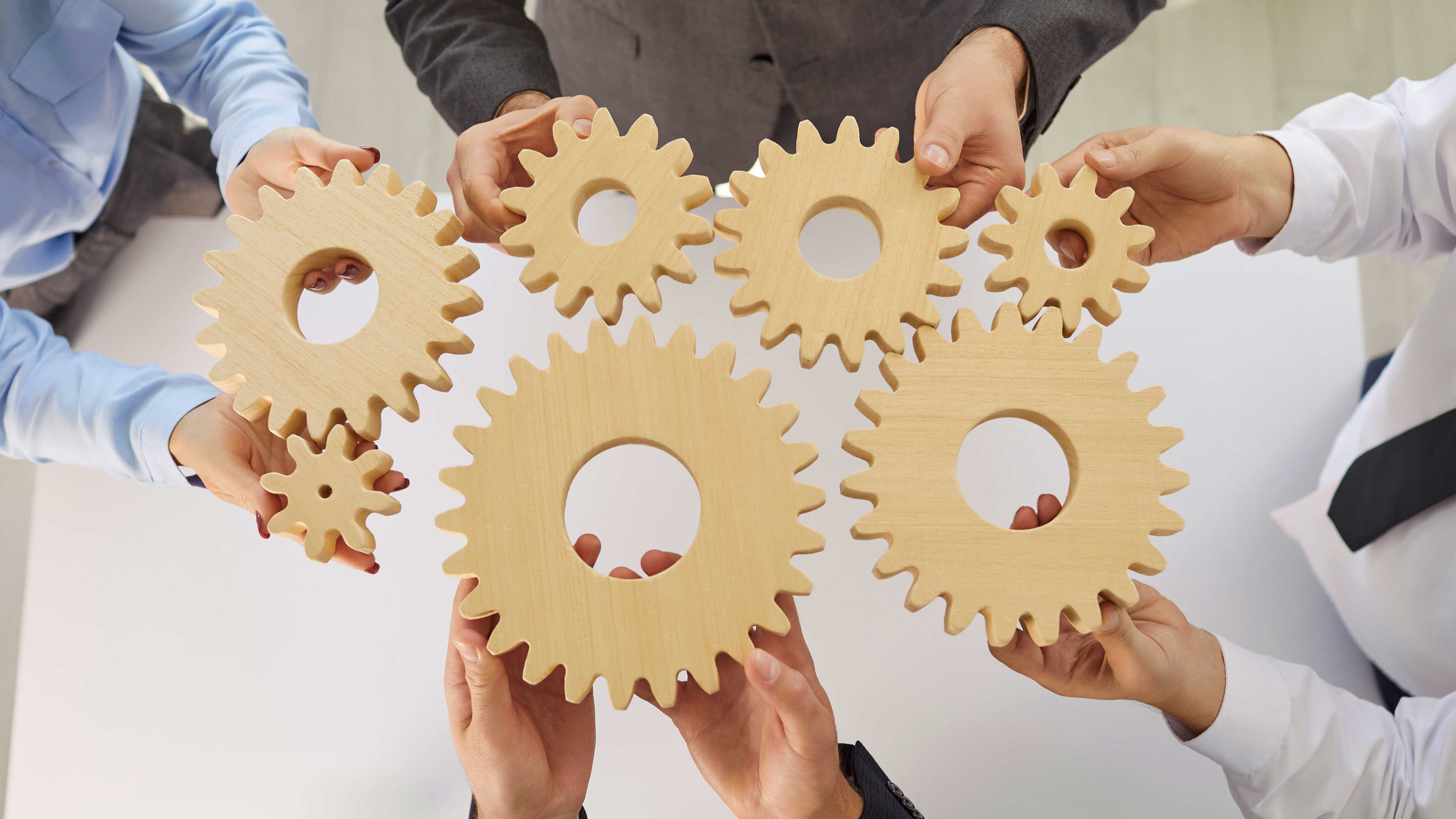 Hænder der holder tandhjul mod hinanden