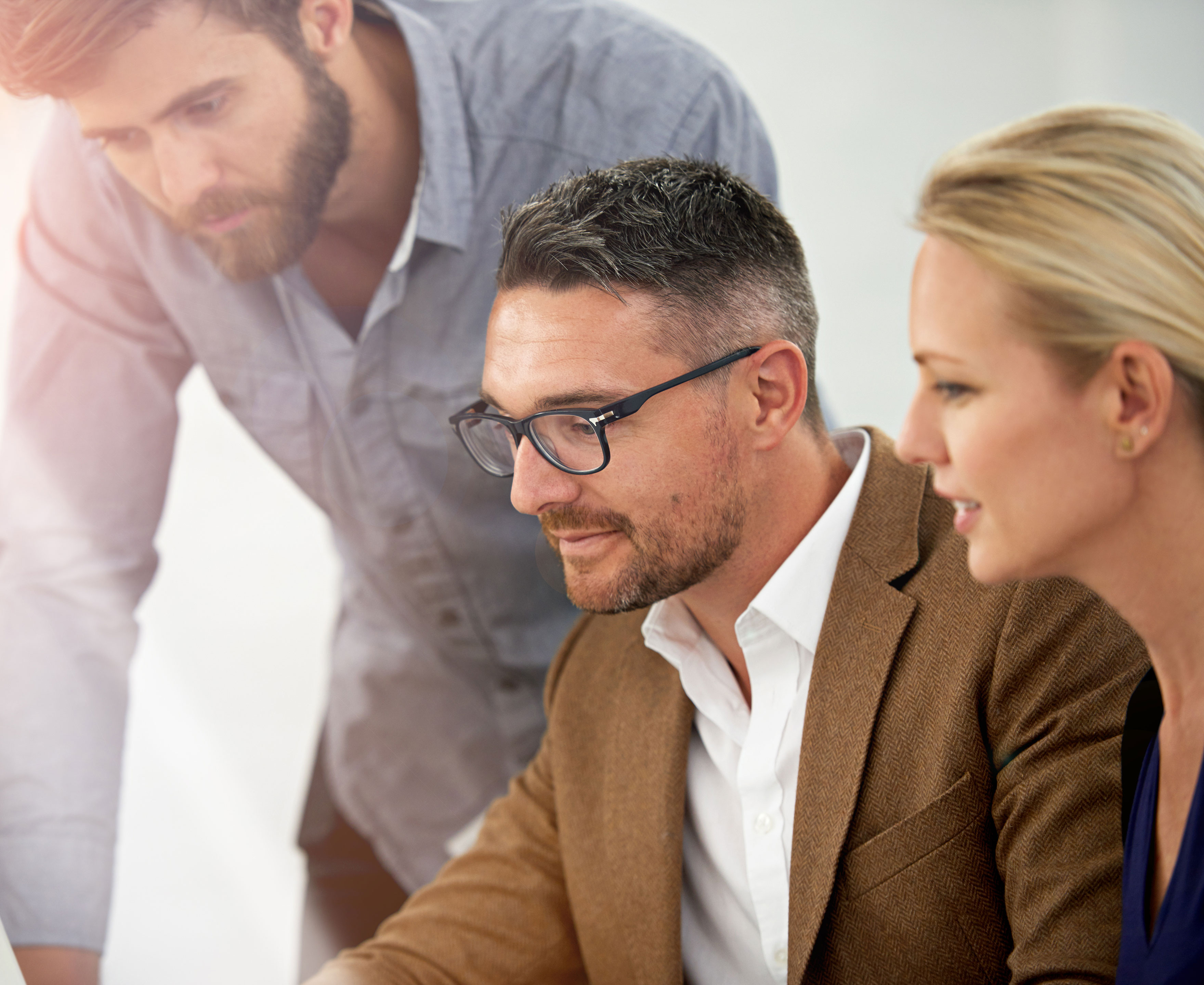 Tre koncentrerede mennesker med blikket rettet mod en PC