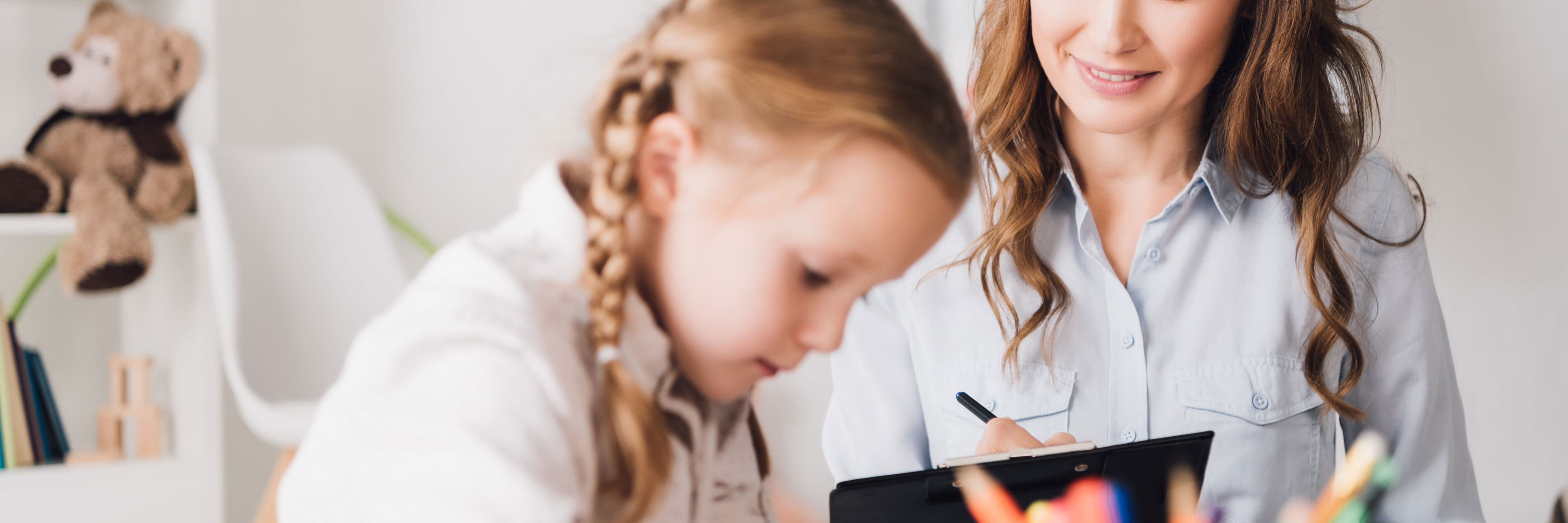 Kvinde sidder med barn der tegner