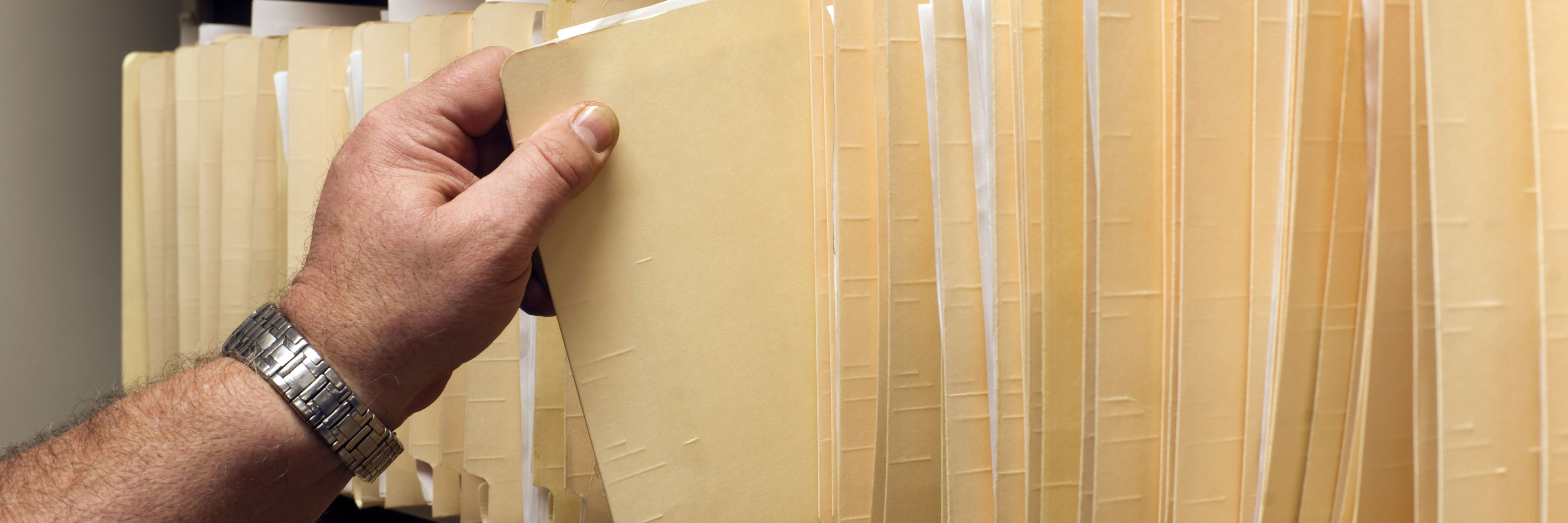 Person tager sagsmappe fra reol