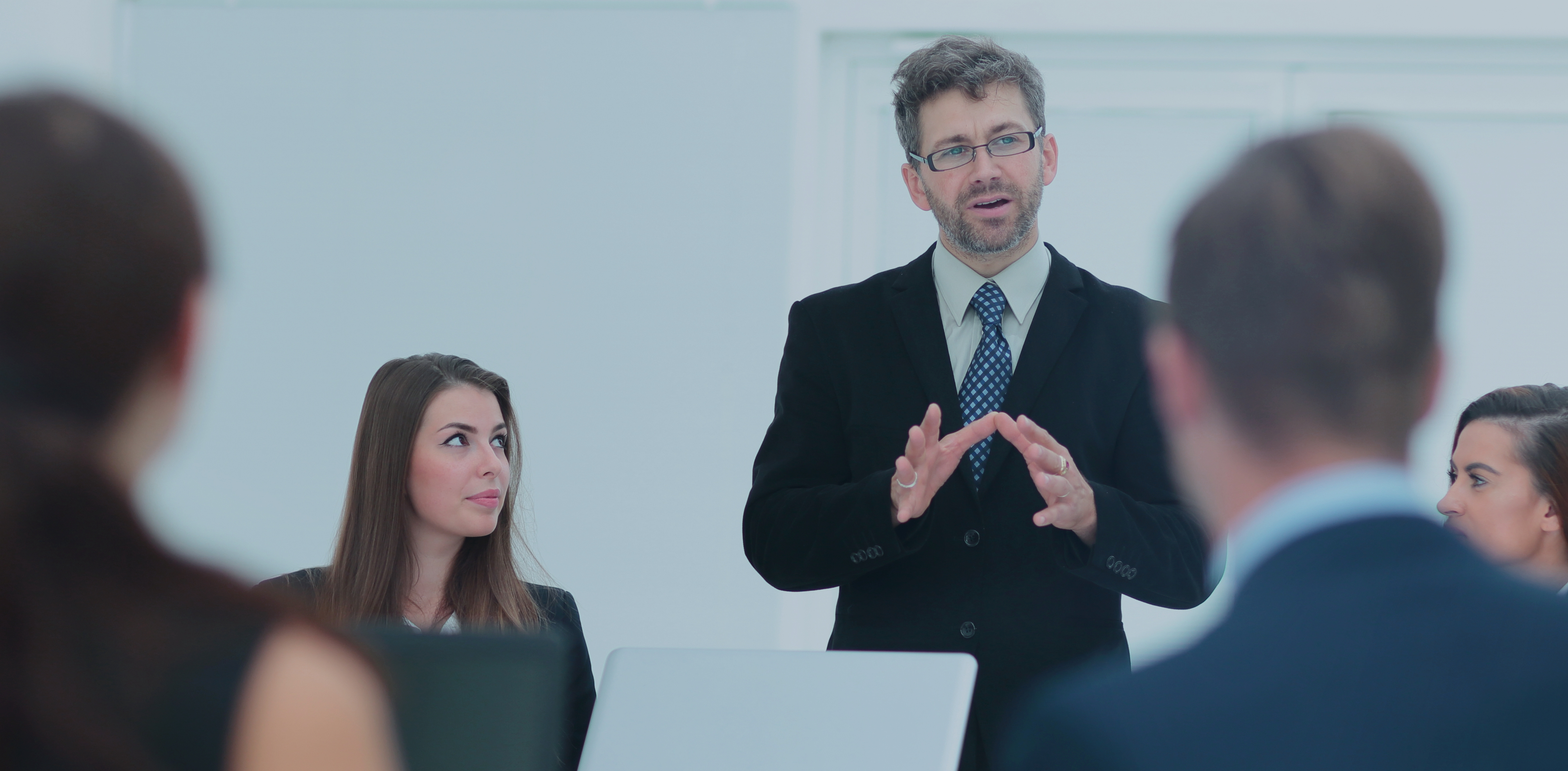 Mand i jakkesæt der taler til en forsamling