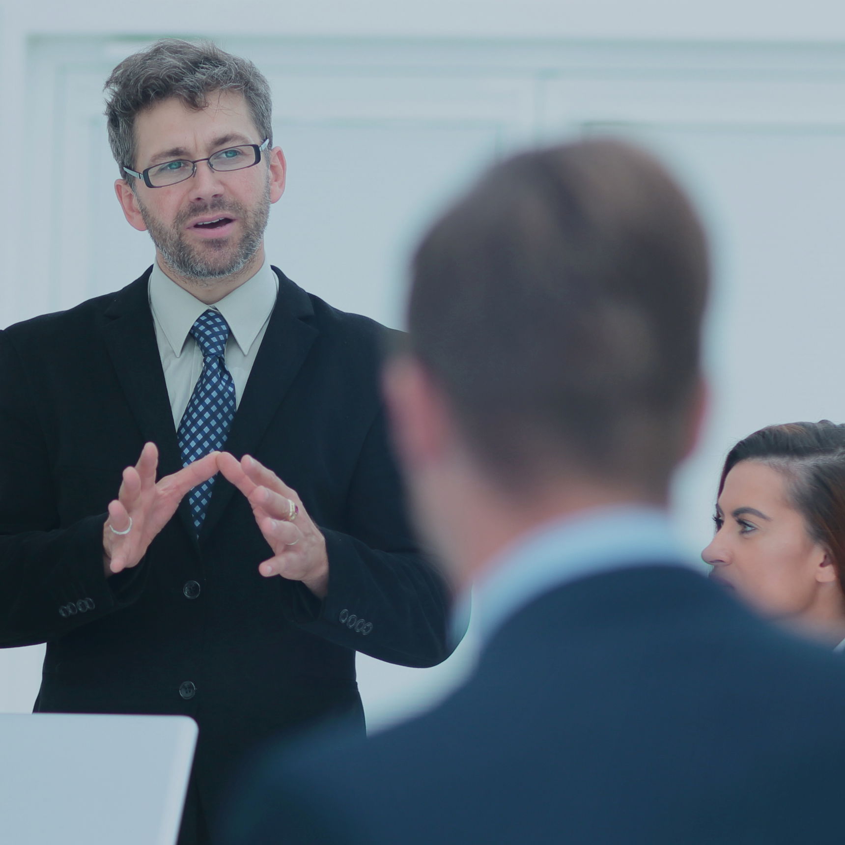 Mand i jakkesæt der taler til en forsamling