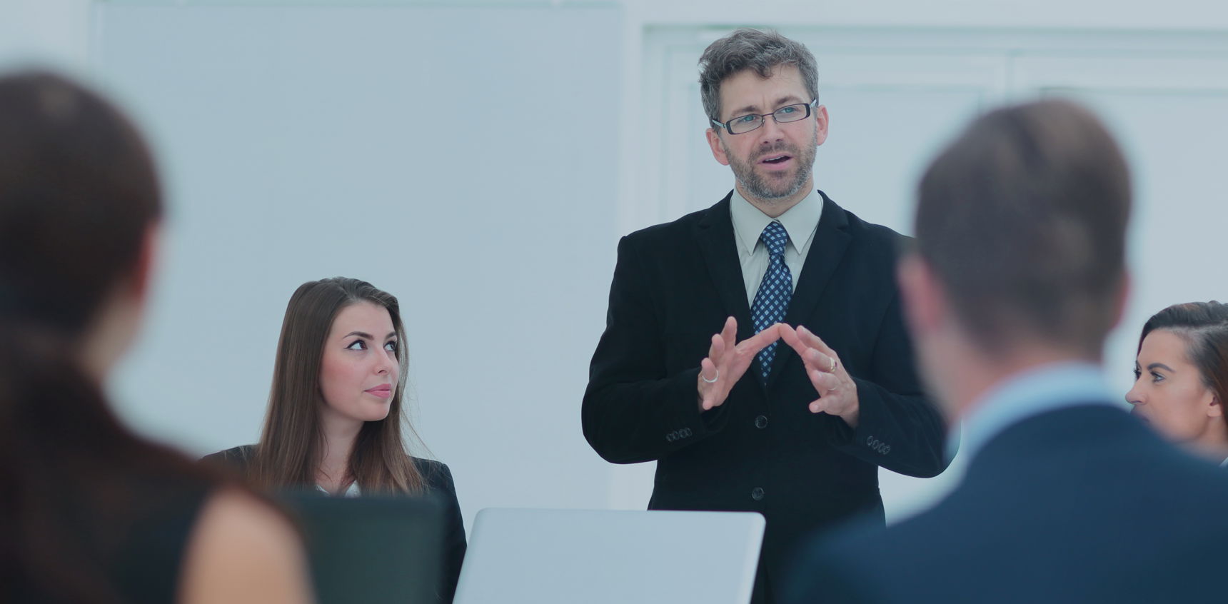 Mand i jakkesæt der taler til en forsamling