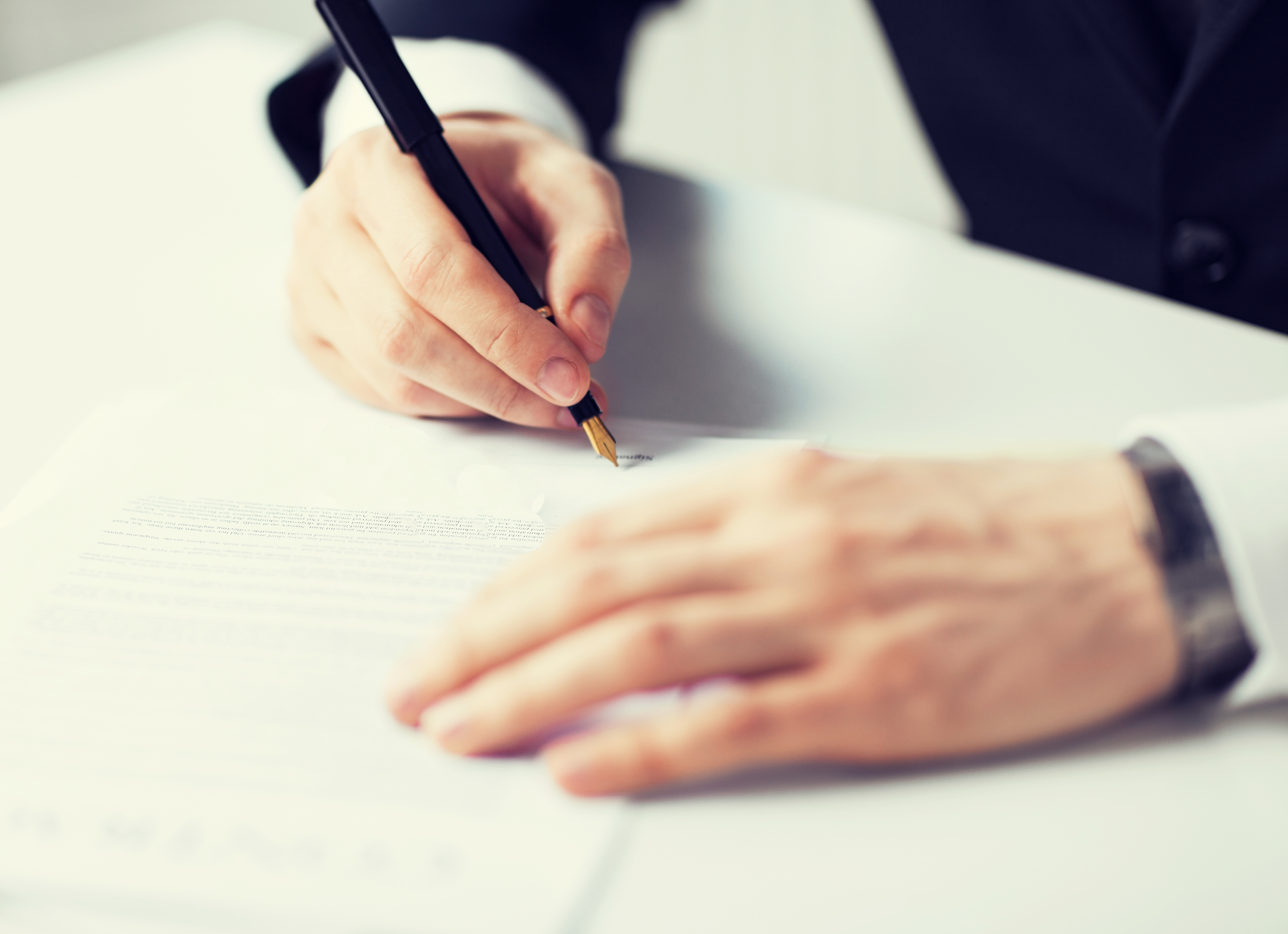 Hånd med kuglepen der underskriver et papir