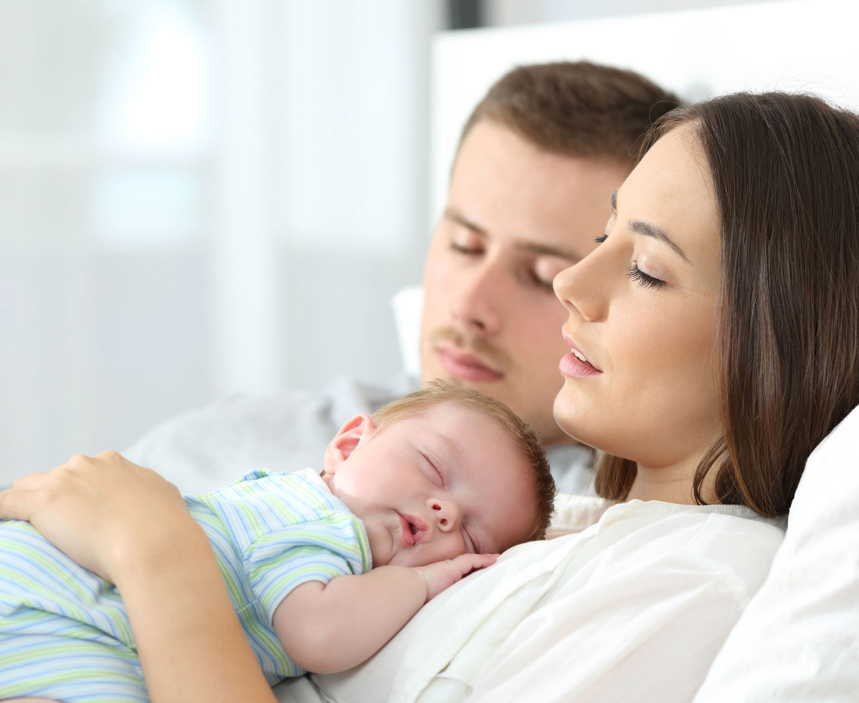 Sovende forældre hvor moren har et sovende spædbarn på maven