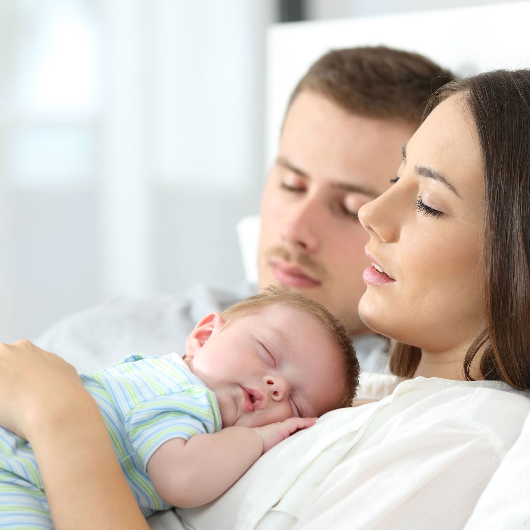 Sovende forældre hvor moren har et sovende spædbarn på maven