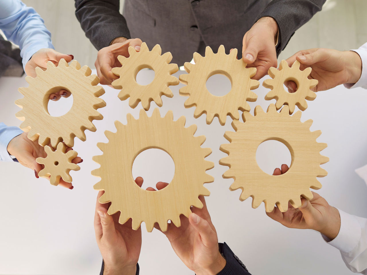 Hænder der holder en masse små tandhjul mod hinanden