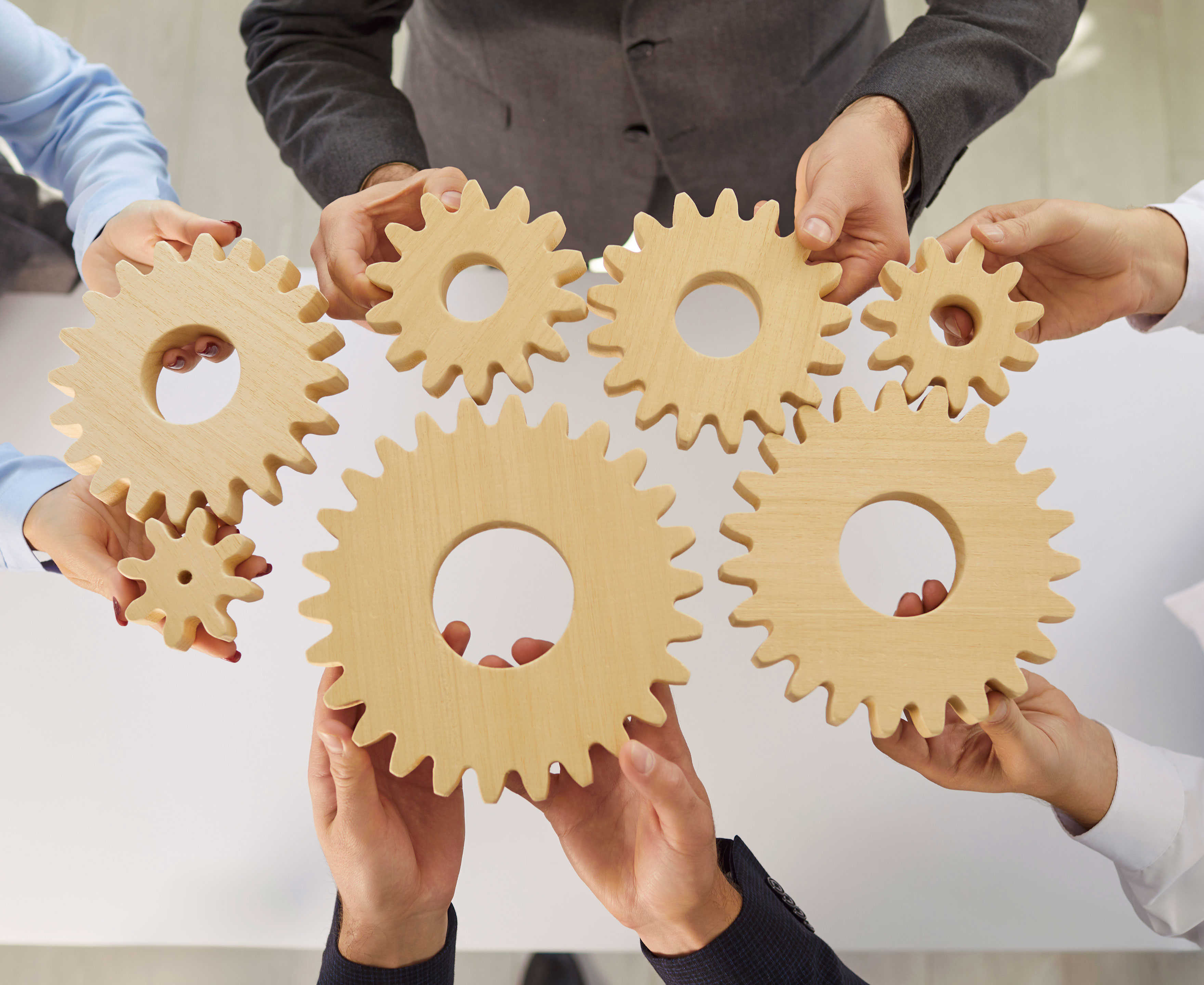 Hænder der holder en masse små tandhjul mod hinanden