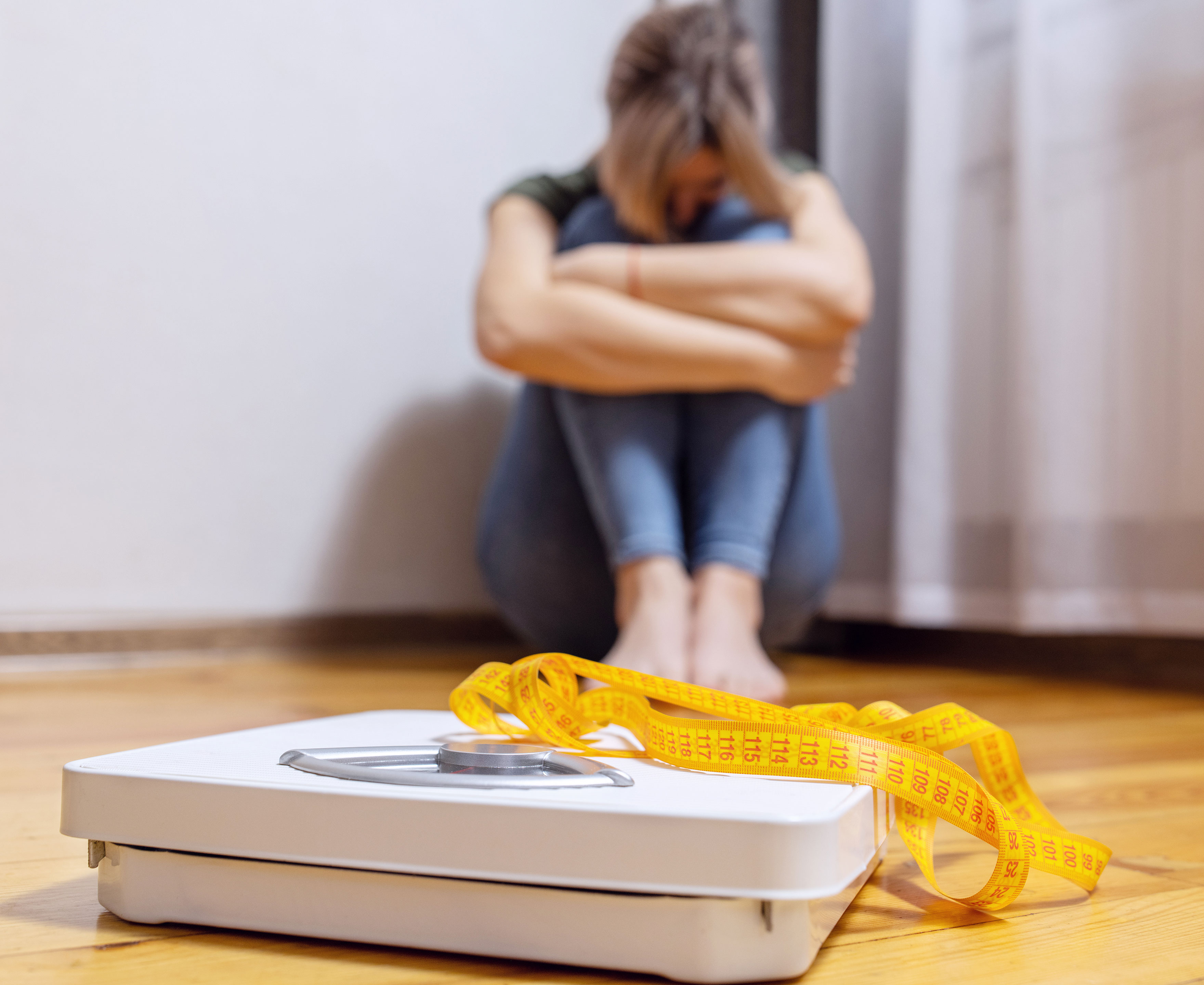 Badevægt med en trist person siddende i baggrunden