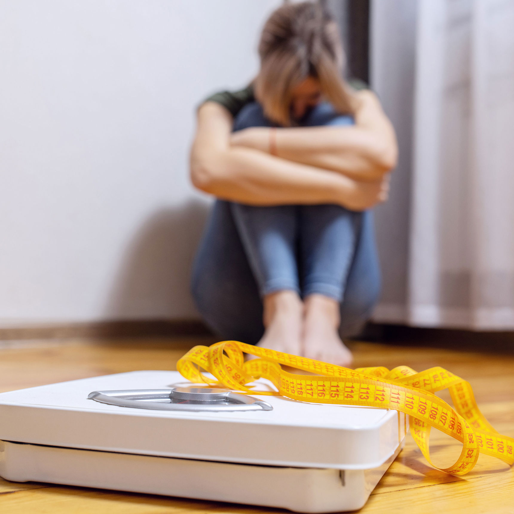 Badevægt med en trist person siddende i baggrunden