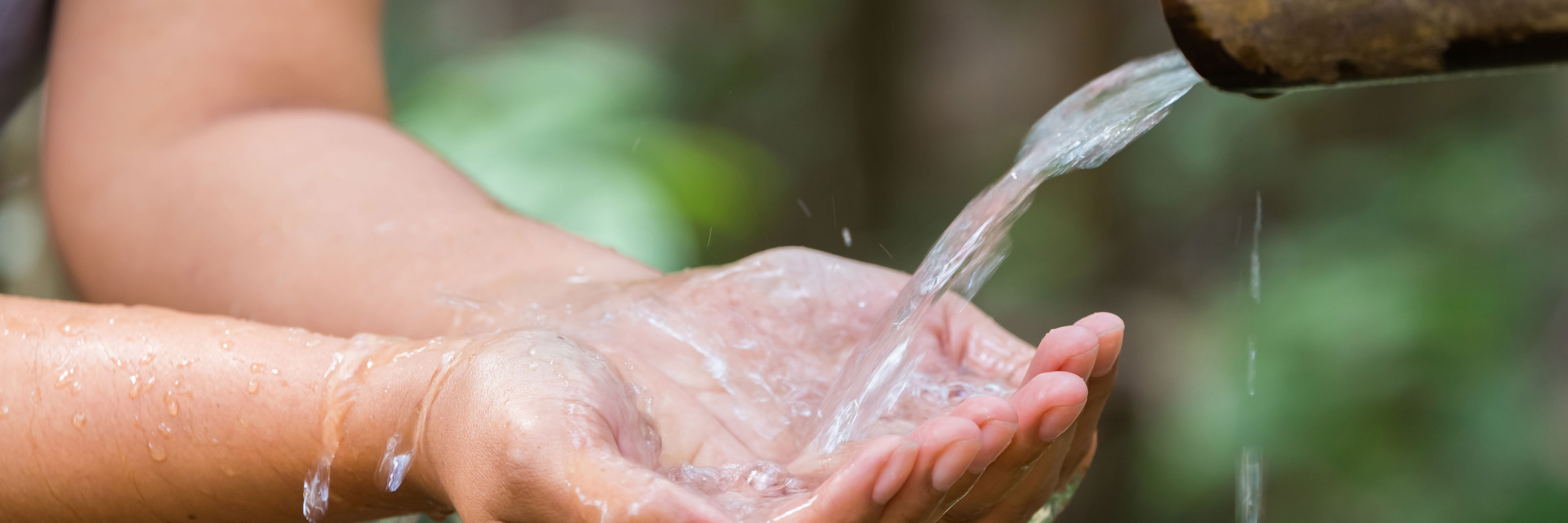 Hænder tager imod vand strømmende fra rør