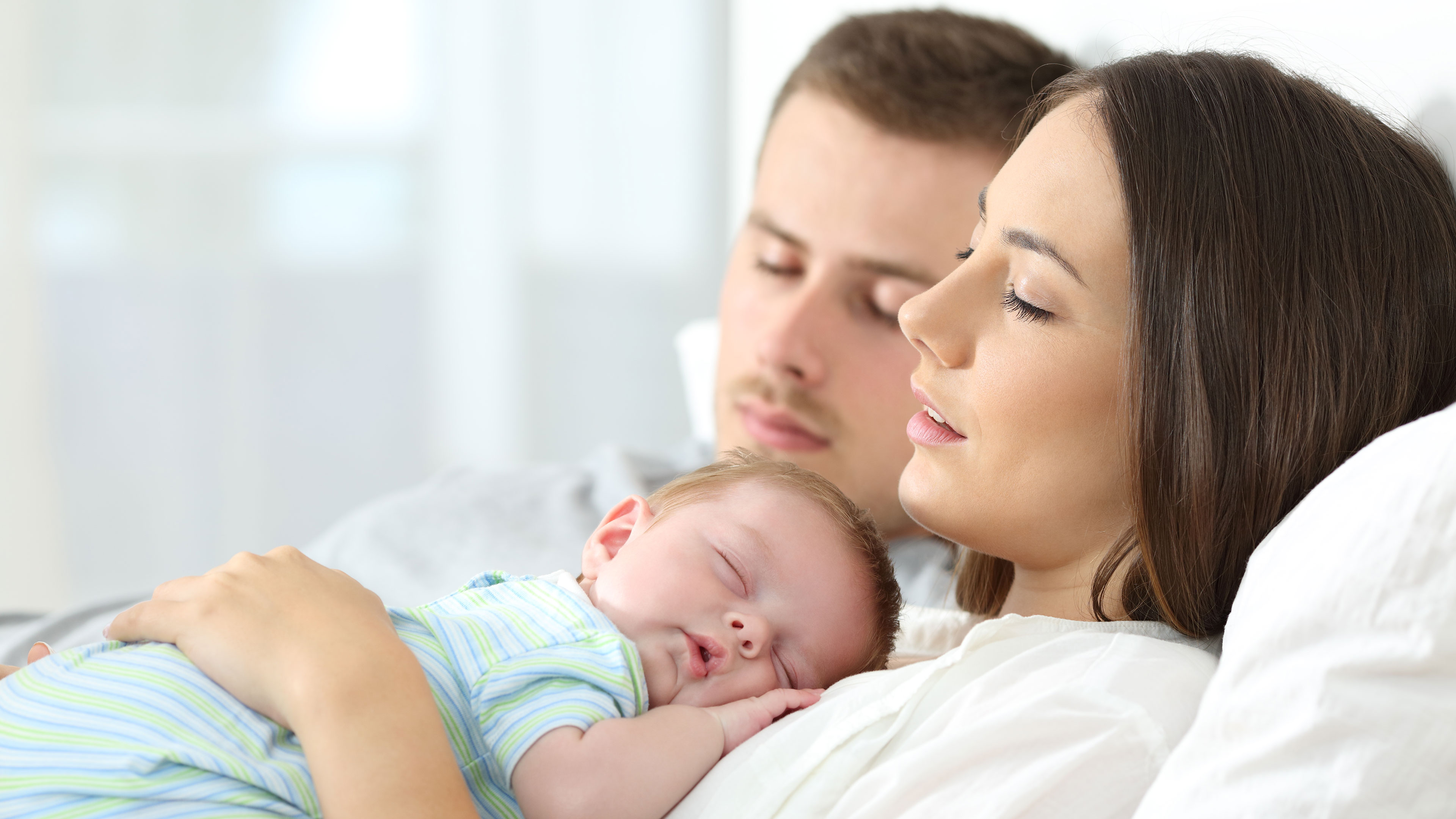 Sovende forældre hvor moren har et sovende spædbarn på maven