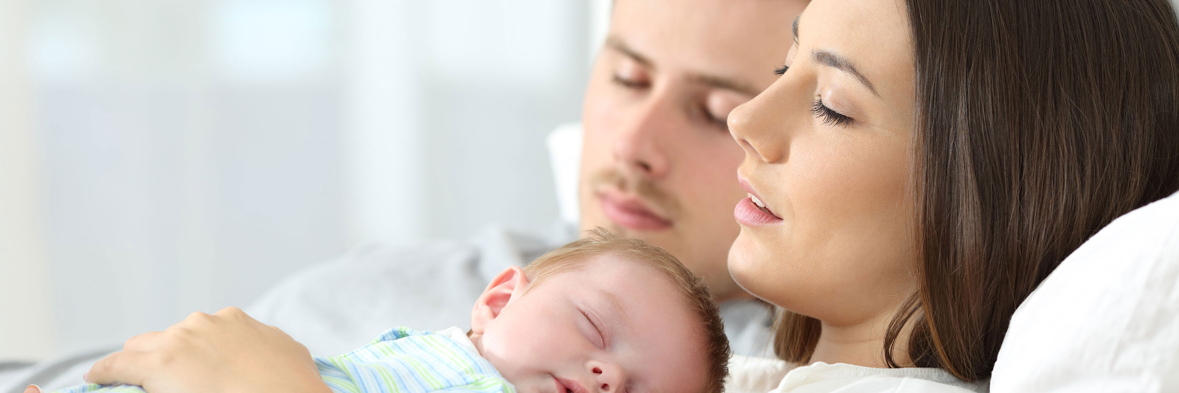 Sovende forældre hvor moren har et sovende spædbarn på maven