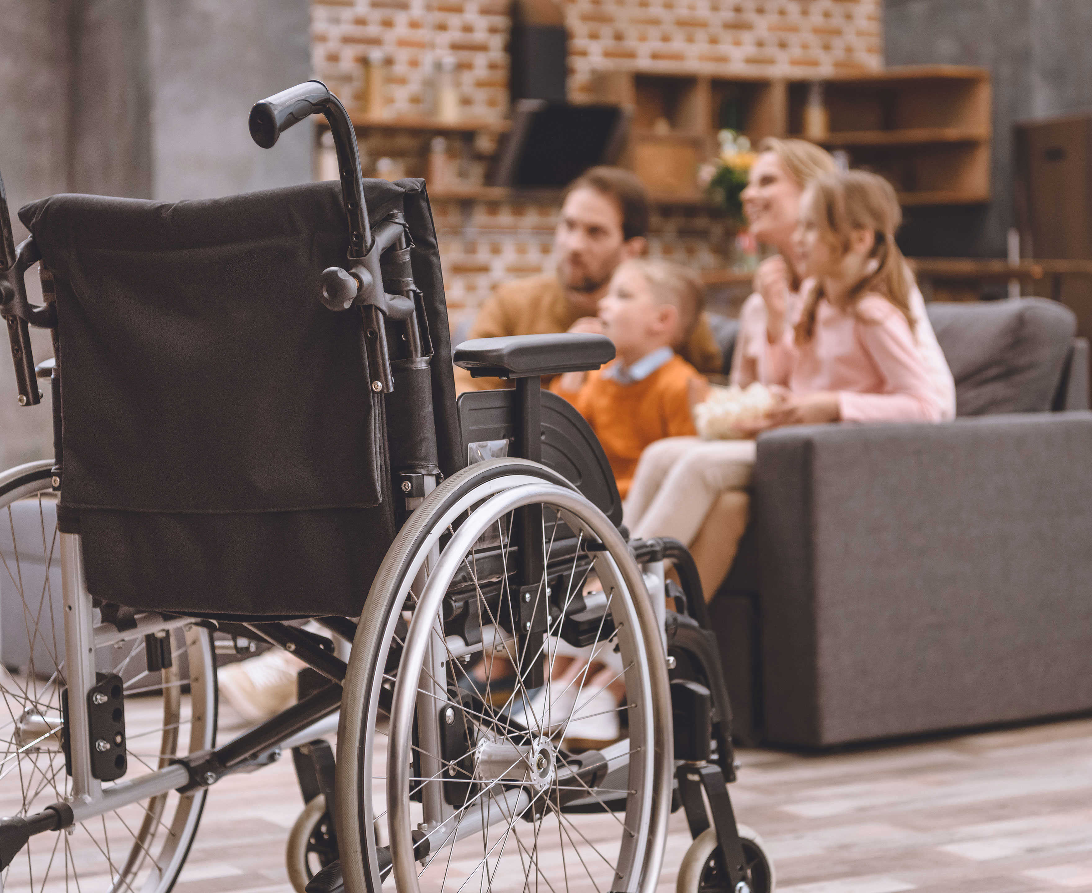 Close up af en kørestol med en familie i baggrunden
