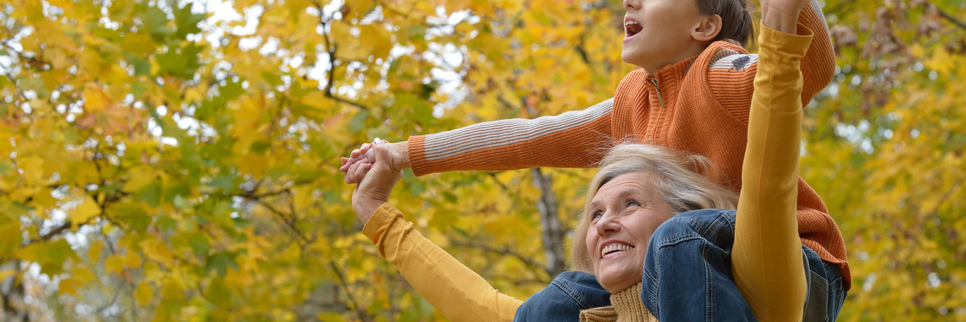 Dreng der sidder på skulderne af sin bedstemor i skoven