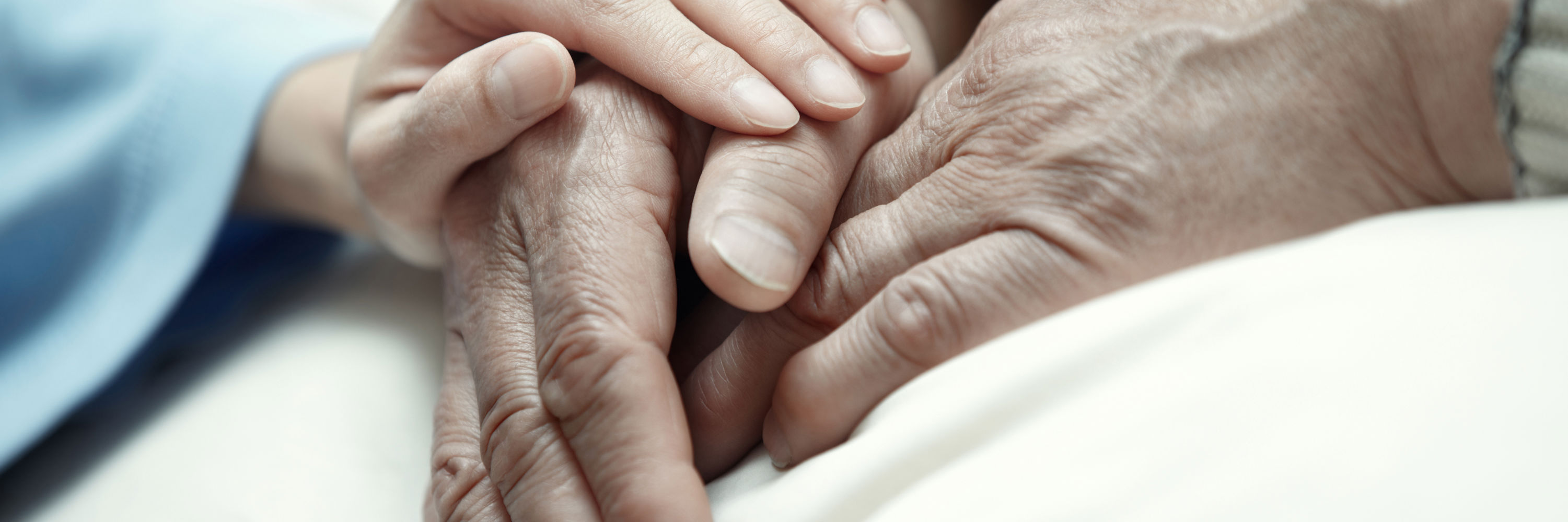 Kvindehånd der ligger på en ældre persons hænder