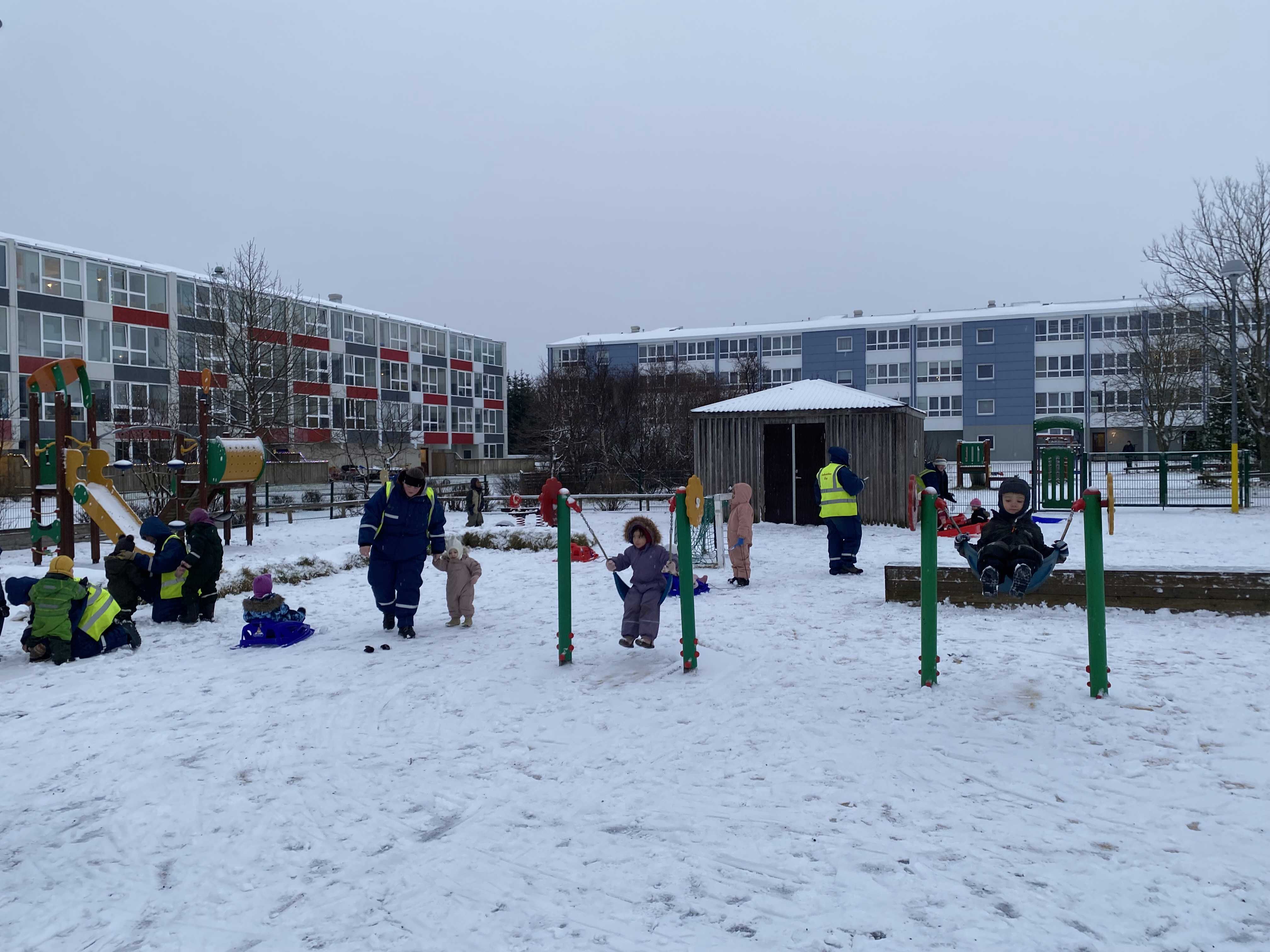 Børn der leger på en legeplads i snevejr i Island