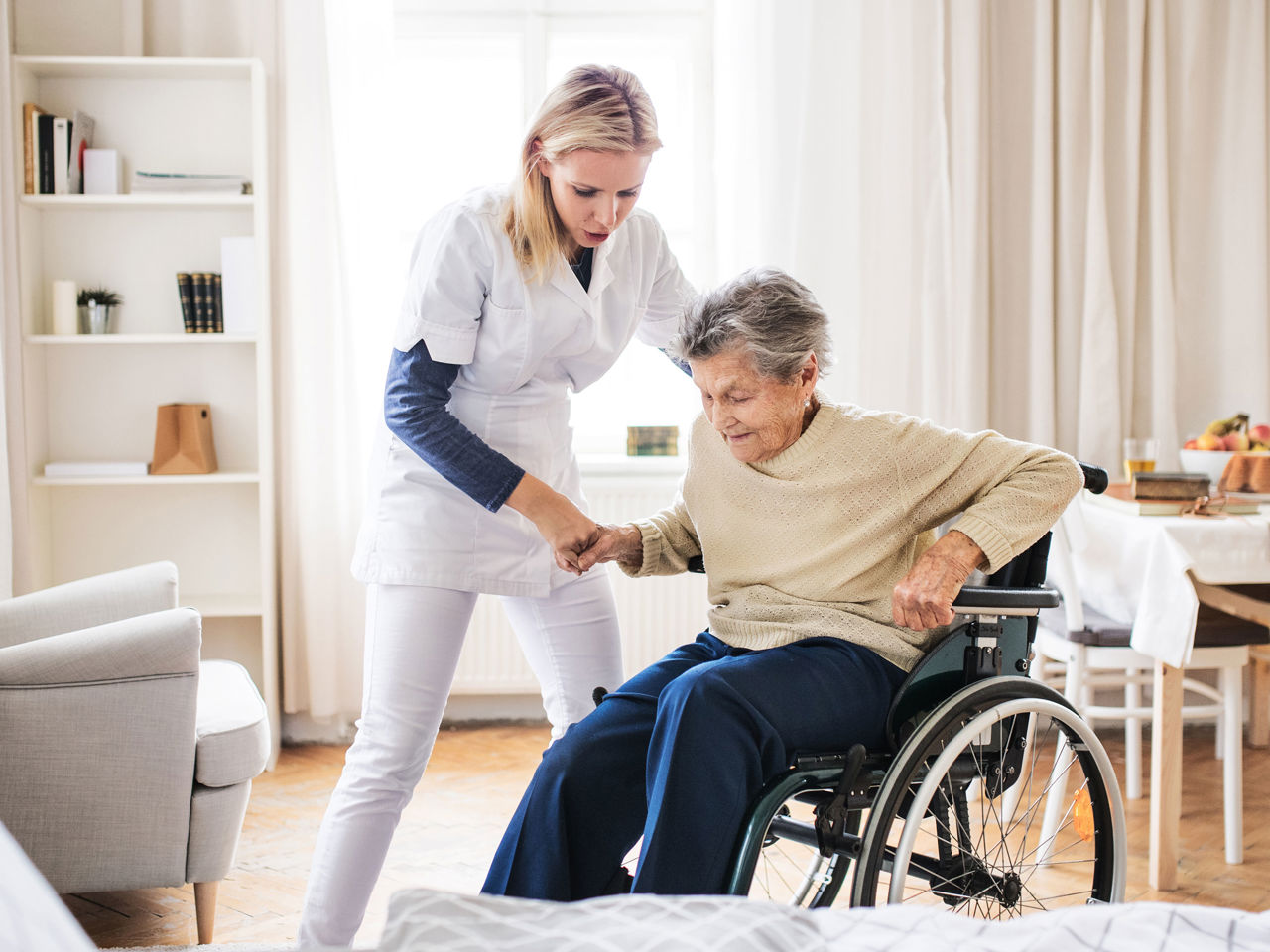 Plejer der taler med en ældre dame i rullestol