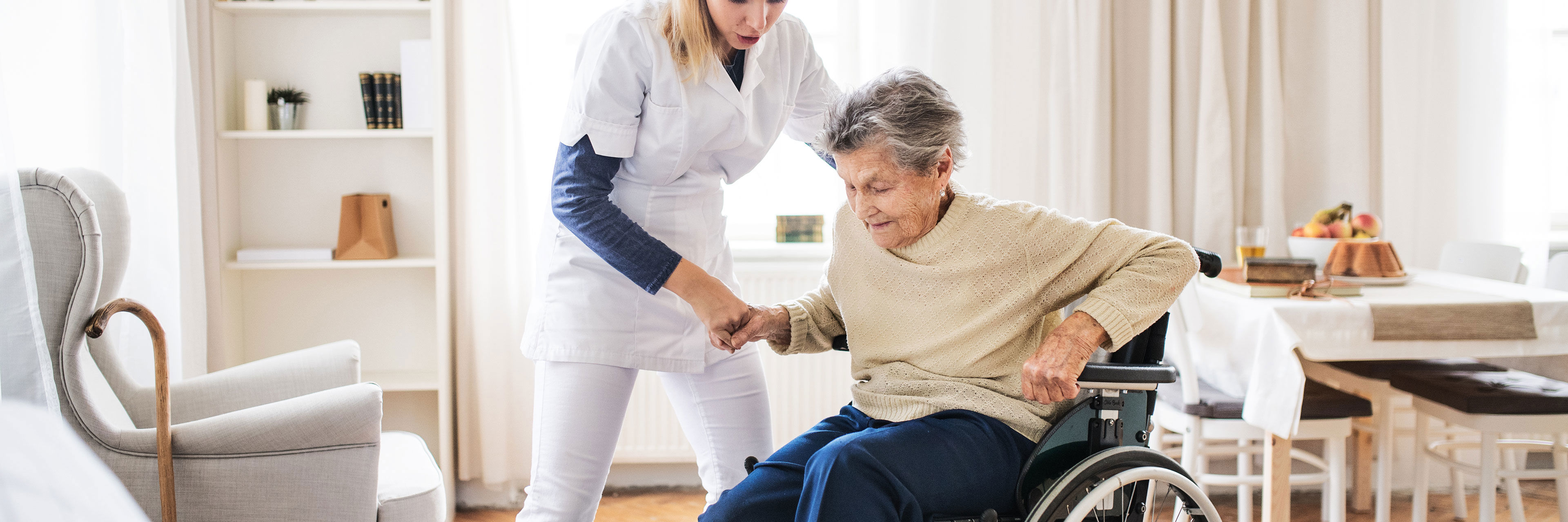 Plejer der taler med en ældre dame i rullestol
